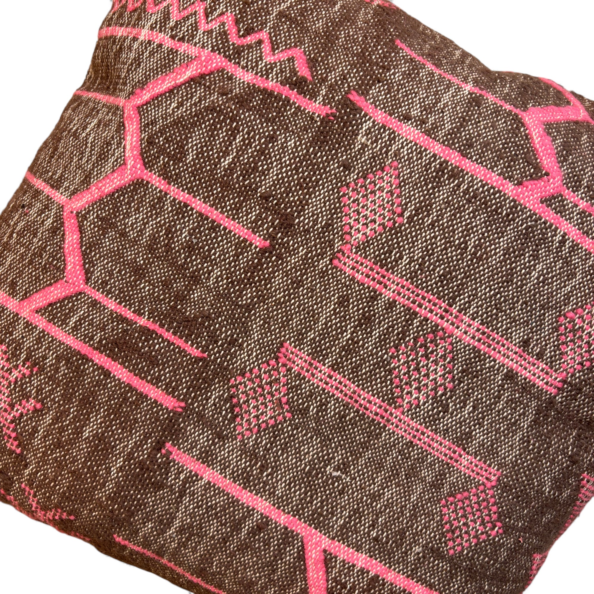Das LEY! Kissen - Colorful Line - Fushia Edition 60x60 von LEY! ist ein braun gewebtes Kissen mit leuchtend rosa geometrischen und Zickzack-Mustern, handgefertigt in Marrakesch aus hochwertiger Schurwolle für eine einzigartige handwerkliche Note.