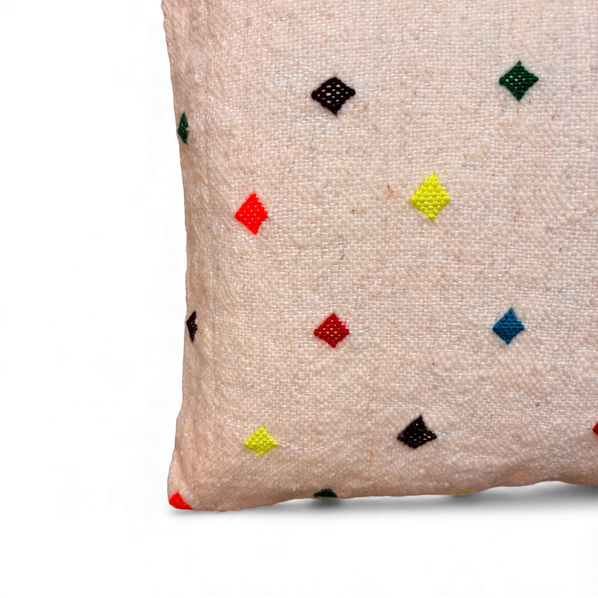 Eine Nahaufnahme des LEY! Kissen - Colorful Line - Gepunktet, 50x50cm, in beige mit kleinen bunten Rautenmustern in rot, gelb, grün, blau und schwarz. Handgefertigt in Marrakesch und vor weißem Hintergrund abgebildet.