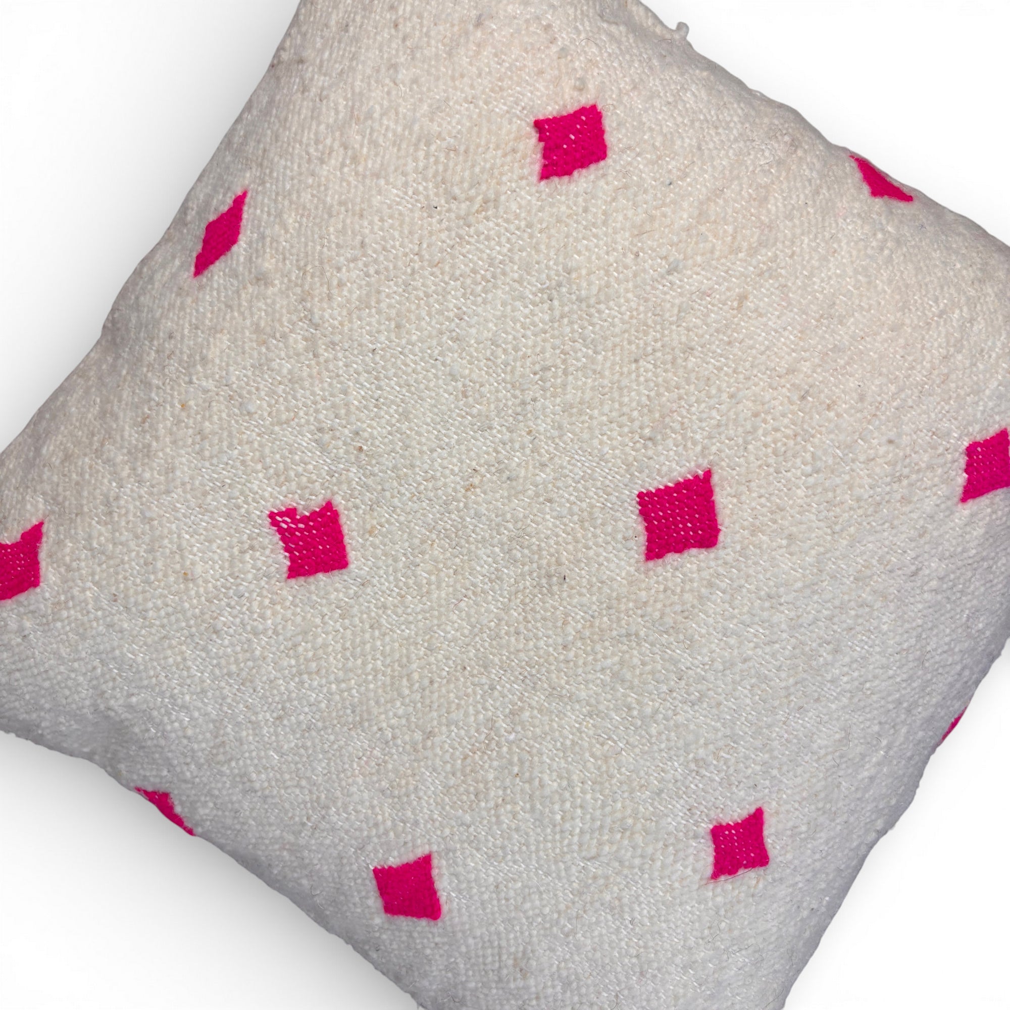 Das LEY! Kissen - Mona Pink - 50 x 50 ist ein quadratisches, cremefarbenes Schurwolle-Kissen mit leuchtend rosafarbenen Rautenmustern, das in Marrakesch handgefertigt wurde und auf einem weißen Hintergrund steht.
