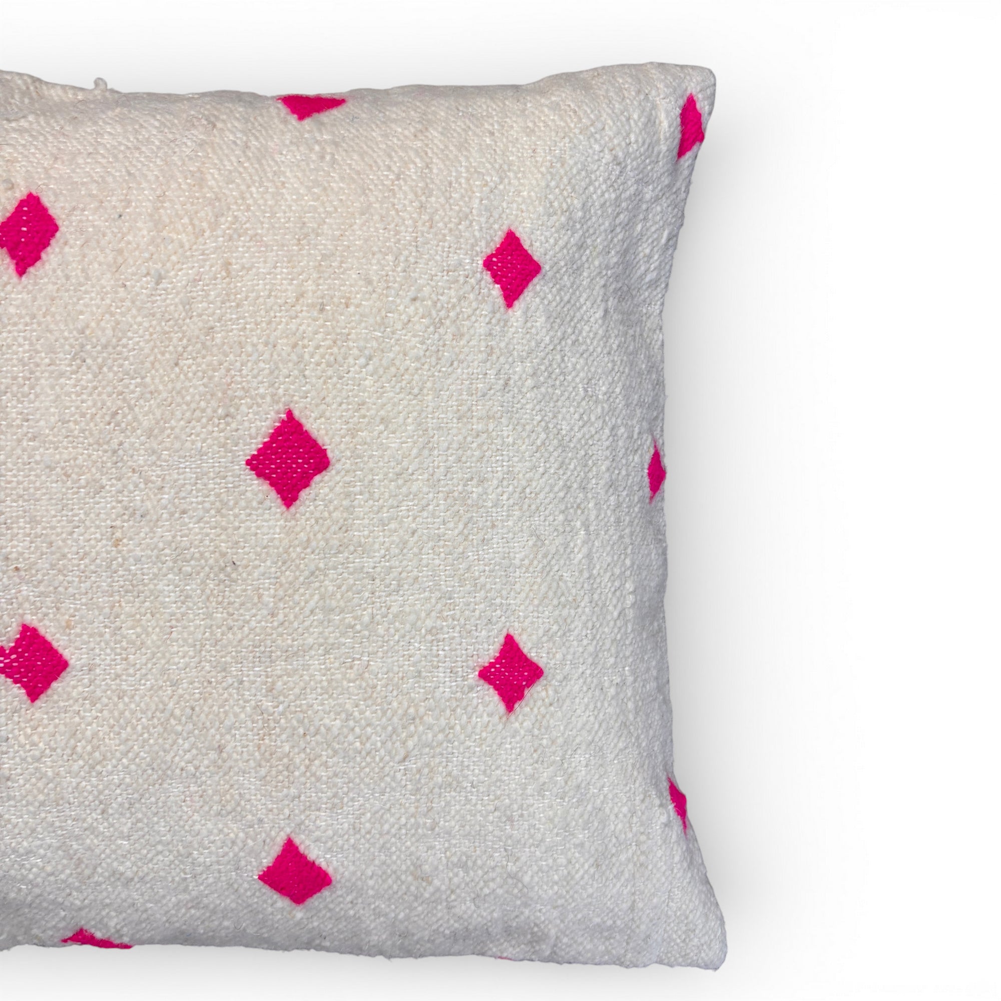 Das LEY! Kissen - Mona Pink - 50 x 50 ist ein weißes, strukturiertes Kissen mit leuchtend rosafarbenen Rautenmustern, die teilweise auf weißem Hintergrund abgebildet sind. Es zeigt exquisite Handarbeit aus Marrakesch.
