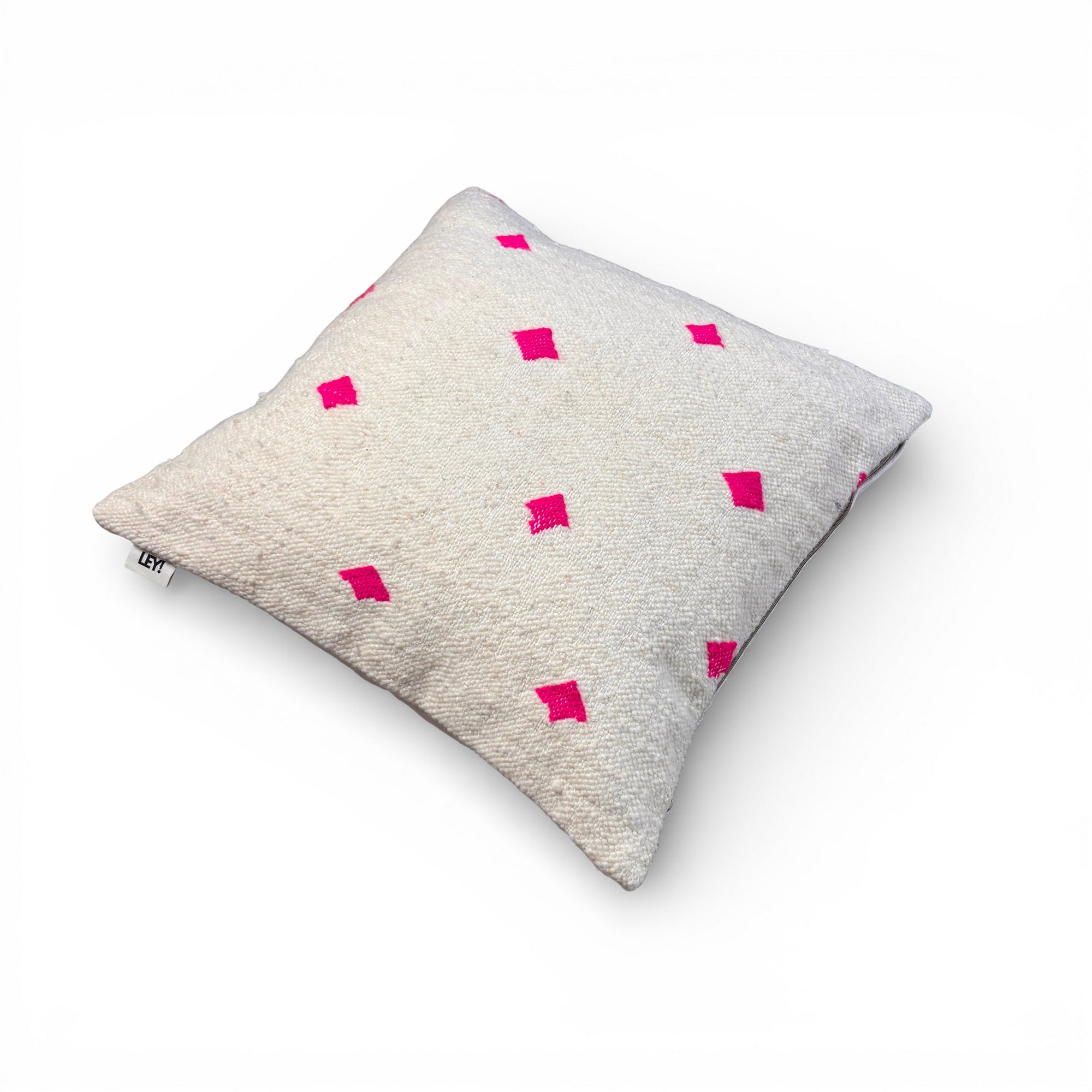 Das LEY! Kissen - Mona Pink - 50 x 50 ist ein quadratisches beigefarbenes Schurwolle-Kissen mit strukturiertem Stoff und gleichmäßig verteilten hellrosa Rauten auf weißem Hintergrund.