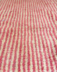 Nahaufnahme des LEY! Berberteppich - Pinq (1,20 x 2,00), mit einer strukturierten, handgewebten Optik in rosa und weißen Streifen; hergestellt aus reiner Schurwolle.