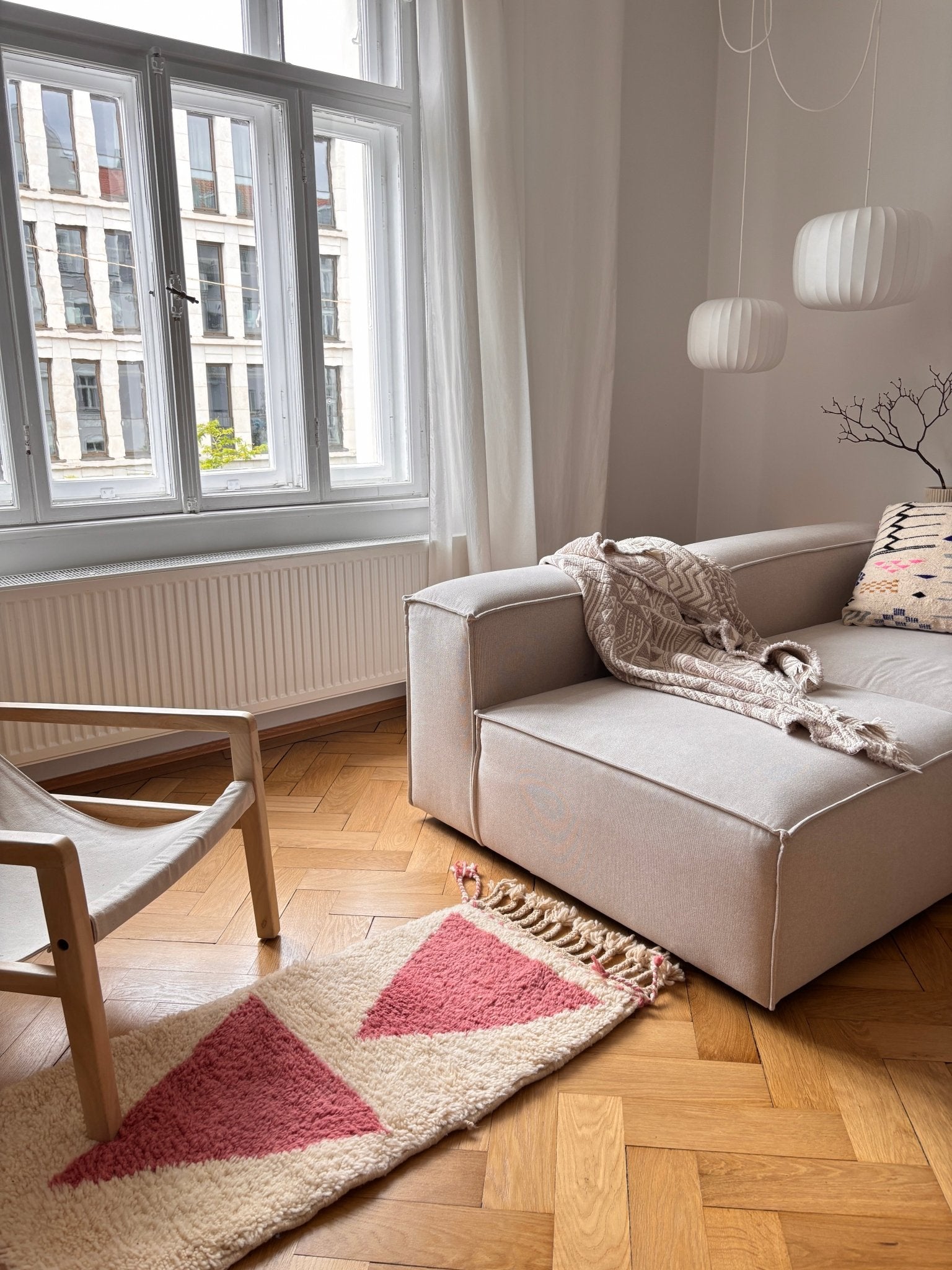 Modernes Wohnzimmer mit einem beigen Sofa, einem Holzstuhl und dem Berber-Teppich „Tazita“ von THE DANISH GIRL INTERIOR.