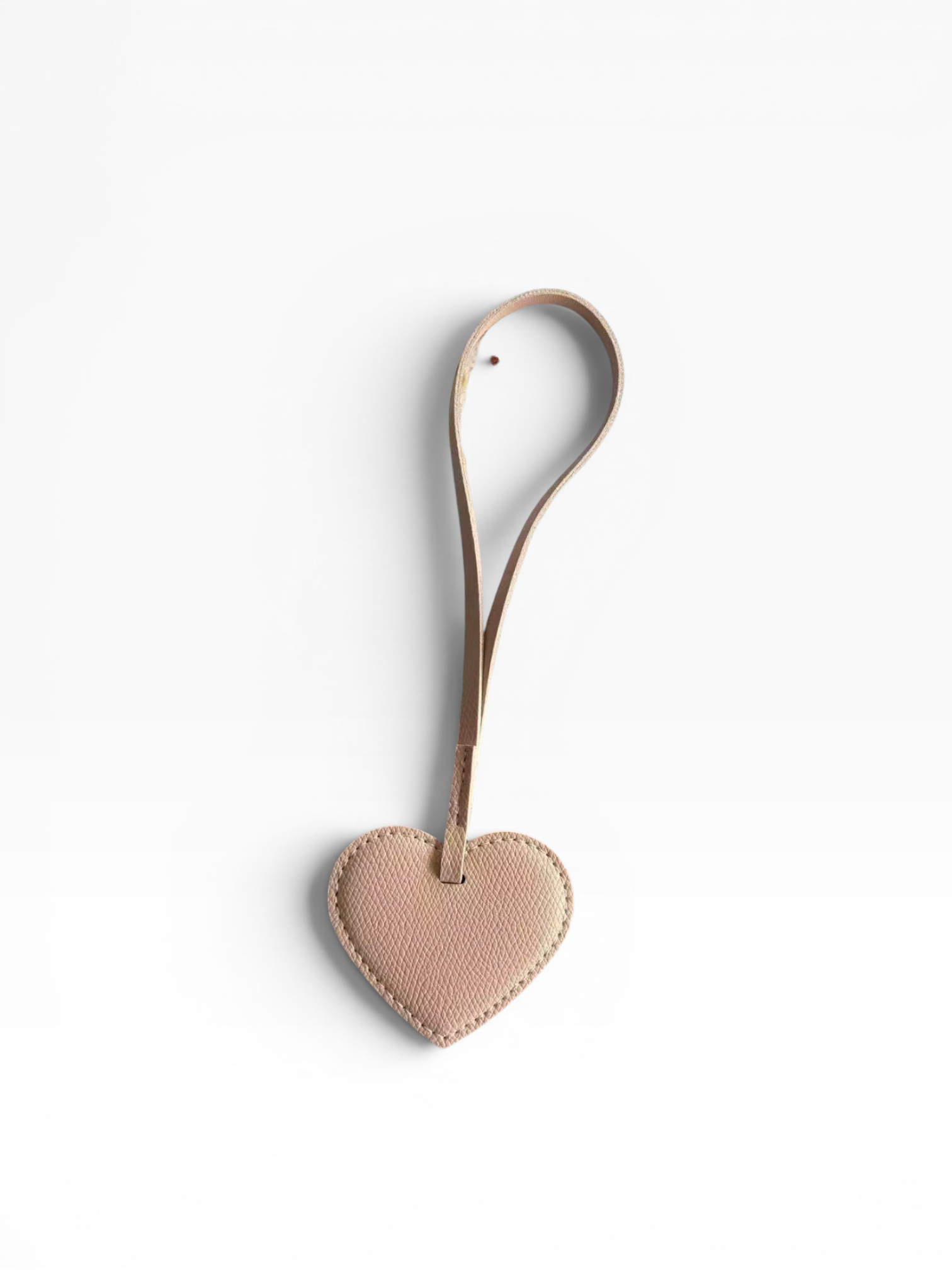 Der LEY! Taschenanhänger – Love Loop in Apricot verfügt über ein geschlungenes Band und wird auf weißem Hintergrund abgebildet.
