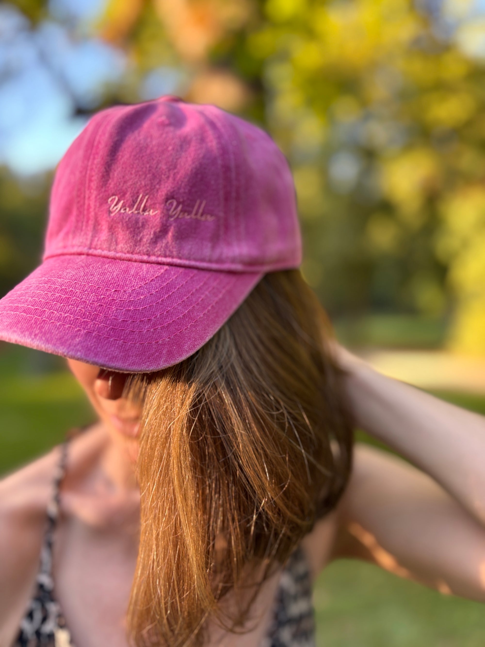 Eine Person trägt die LEY! „Yalla Yalla“-Kappe in Lila im Freien, im Hintergrund sind grüne Bäume schemenhaft zu erkennen.