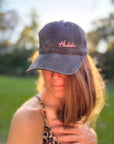 Eine Frau im Freien mit einer rosa LEY! „Habibi“-Kappe mit verstellbarem Riemen, im Hintergrund Sonnenlicht und Bäume.