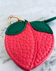 Der Schlüsselanhänger - Pfirsich von LEY! ist ein kleiner, strukturierter, rosafarbener Anhänger in Pfirsichform mit grünen Blättern und einer goldenen Schließe - ideal als Mini-Etui aus Kunstleder für Ihre Essentials.