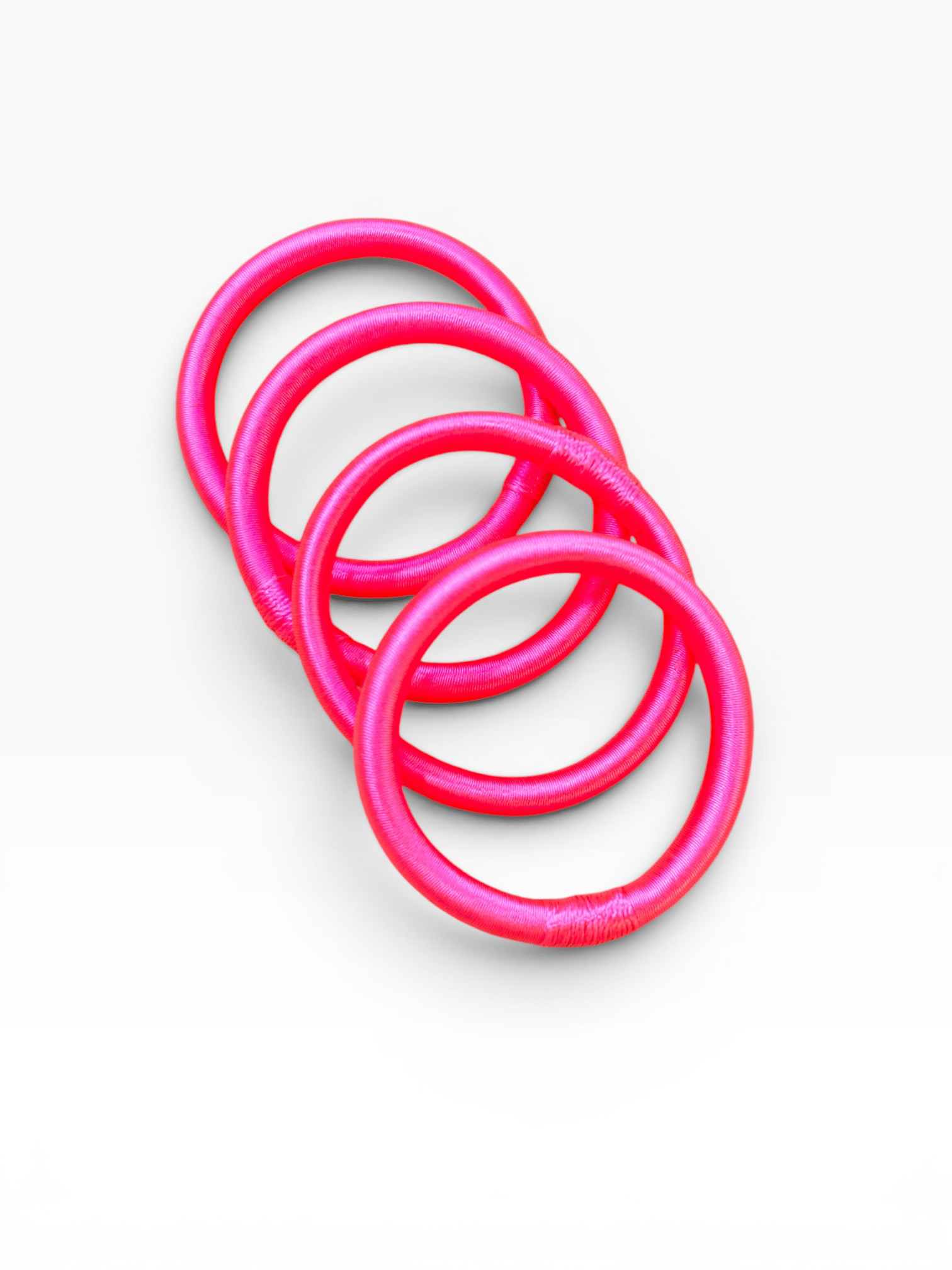 LEY! Armreif „Minama“ in Neonrosa, marokkanisch inspiriert, diagonal auf weißem Hintergrund angeordnet.