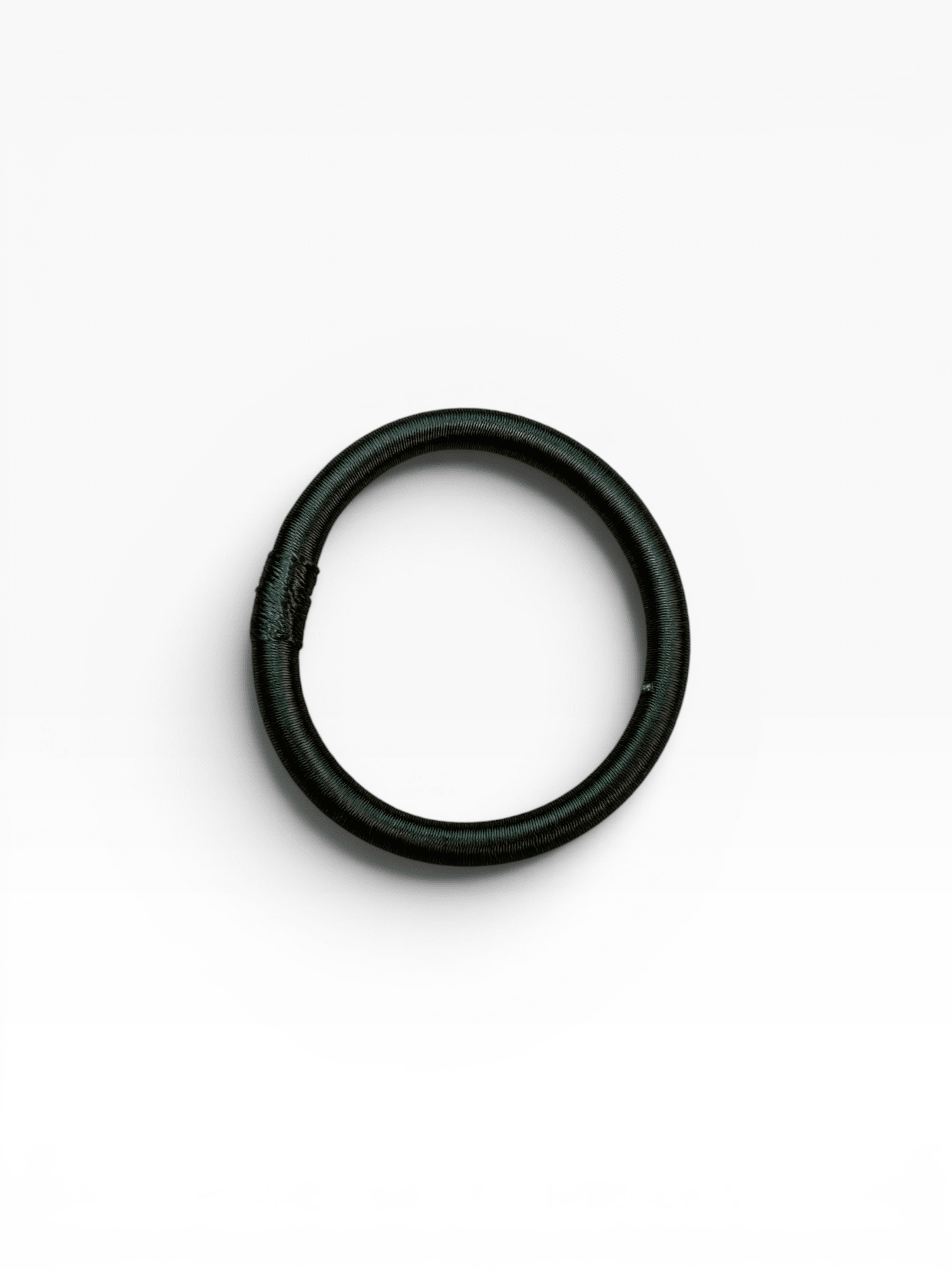 Ein einzelner LEY! Armreif – Minama – dunkelgrün ist zu einem Ring gewunden und liegt auf einem weißen Hintergrund.