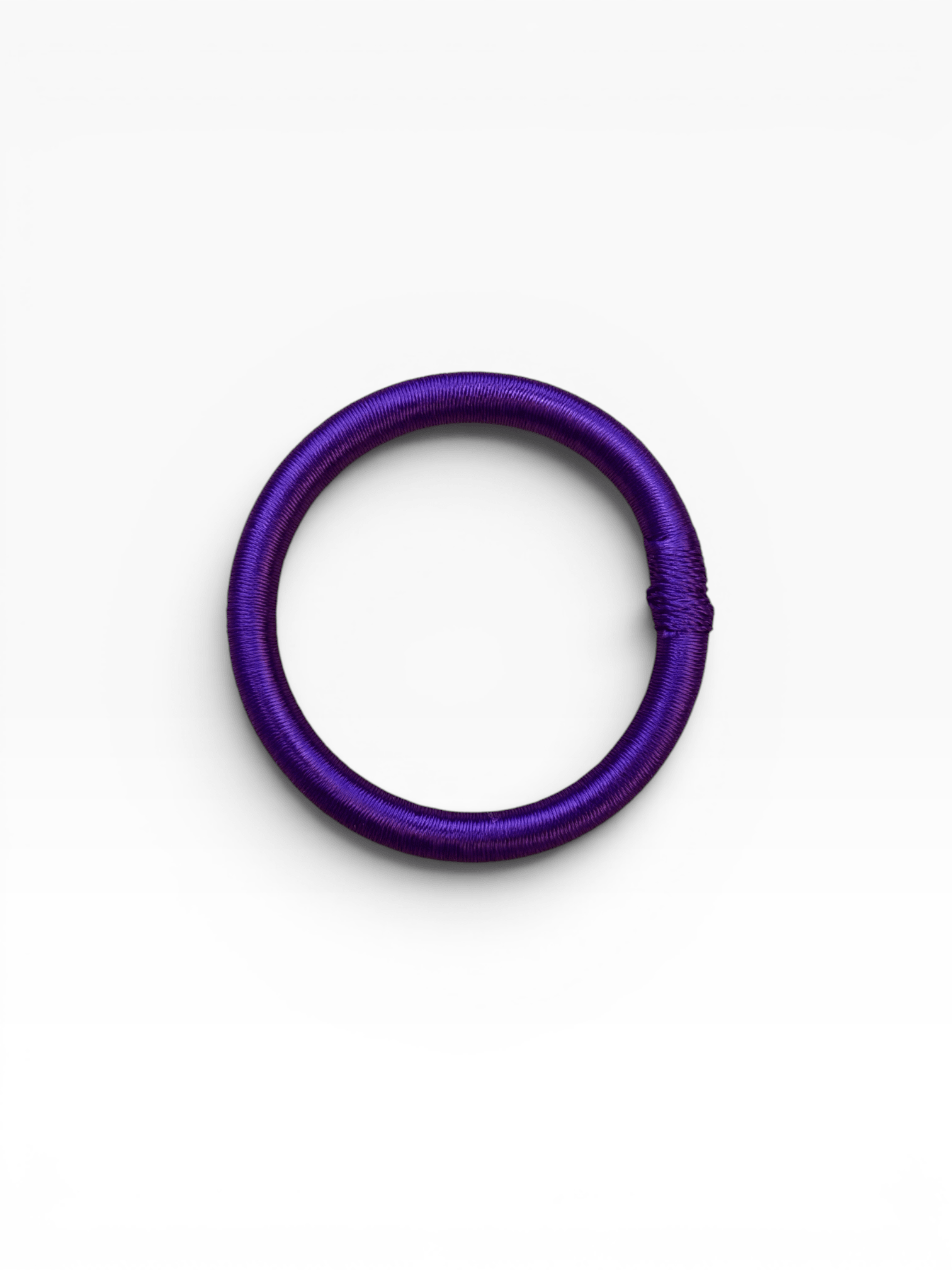 Ein violetter LEY! Armreif – Minama – in Lila liegt flach auf einem weißen Hintergrund und erinnert an ein Haargummi.
