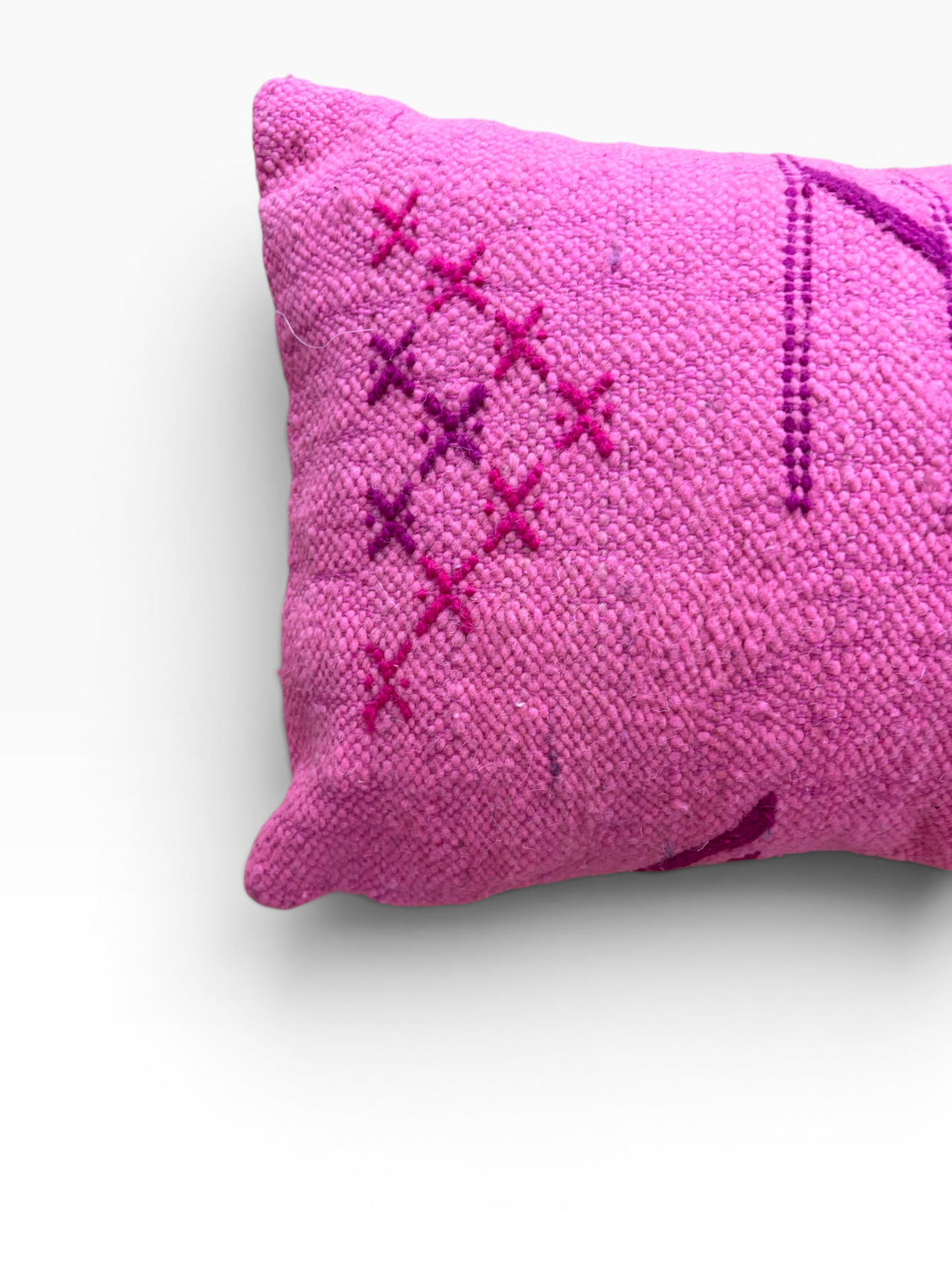 Das LEY! Kissen „Colorful Line Pink Edition“ (30 x 50) besticht durch violette Kreuzstiche auf rosa Stoff vor weißem Hintergrund.