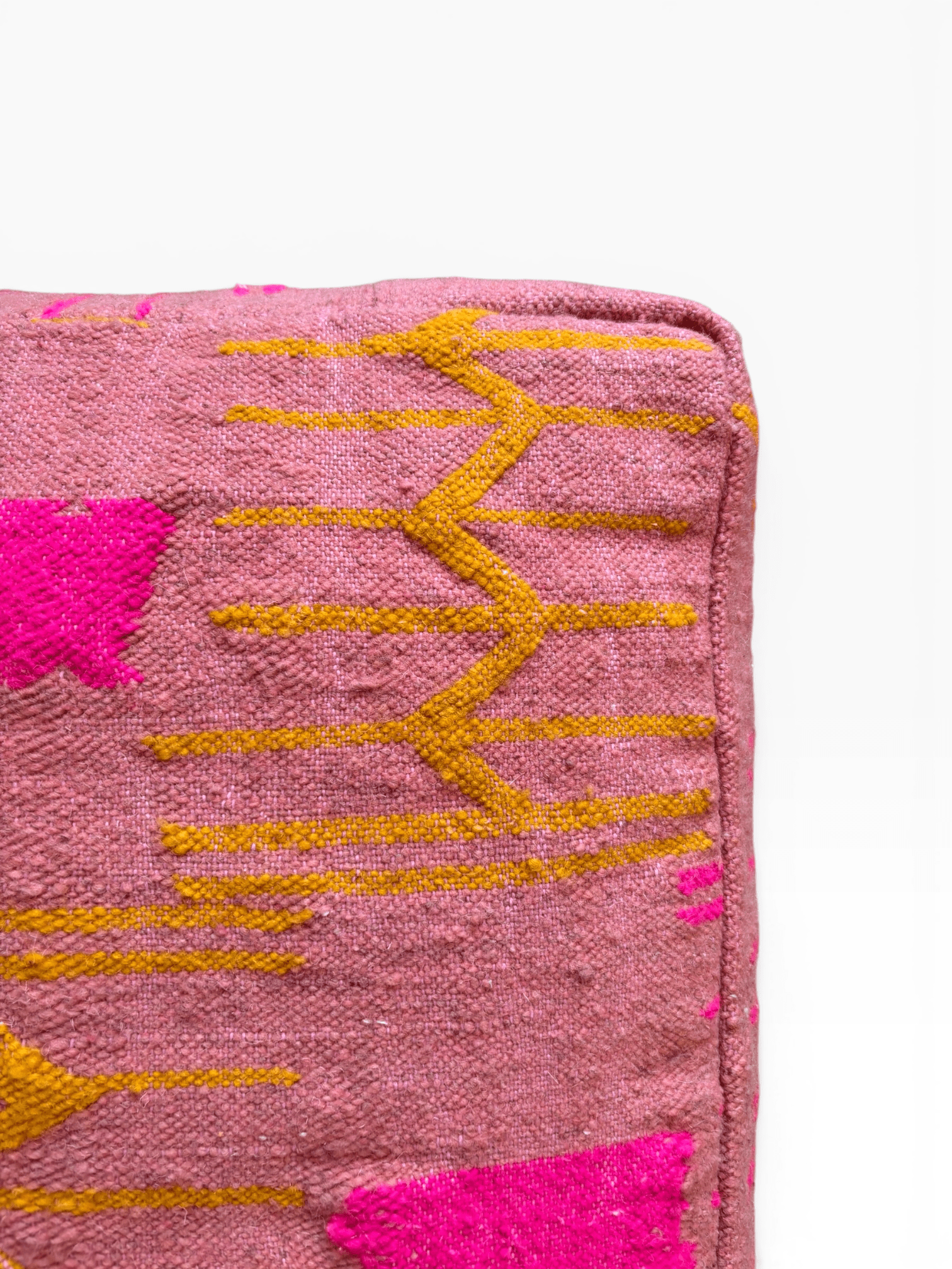 Nahaufnahme von LEY! Bodenkissen – Colorful Line Terra III in Terrakotta mit gelbem Zickzackmuster und leuchtend pinken Akzenten.
