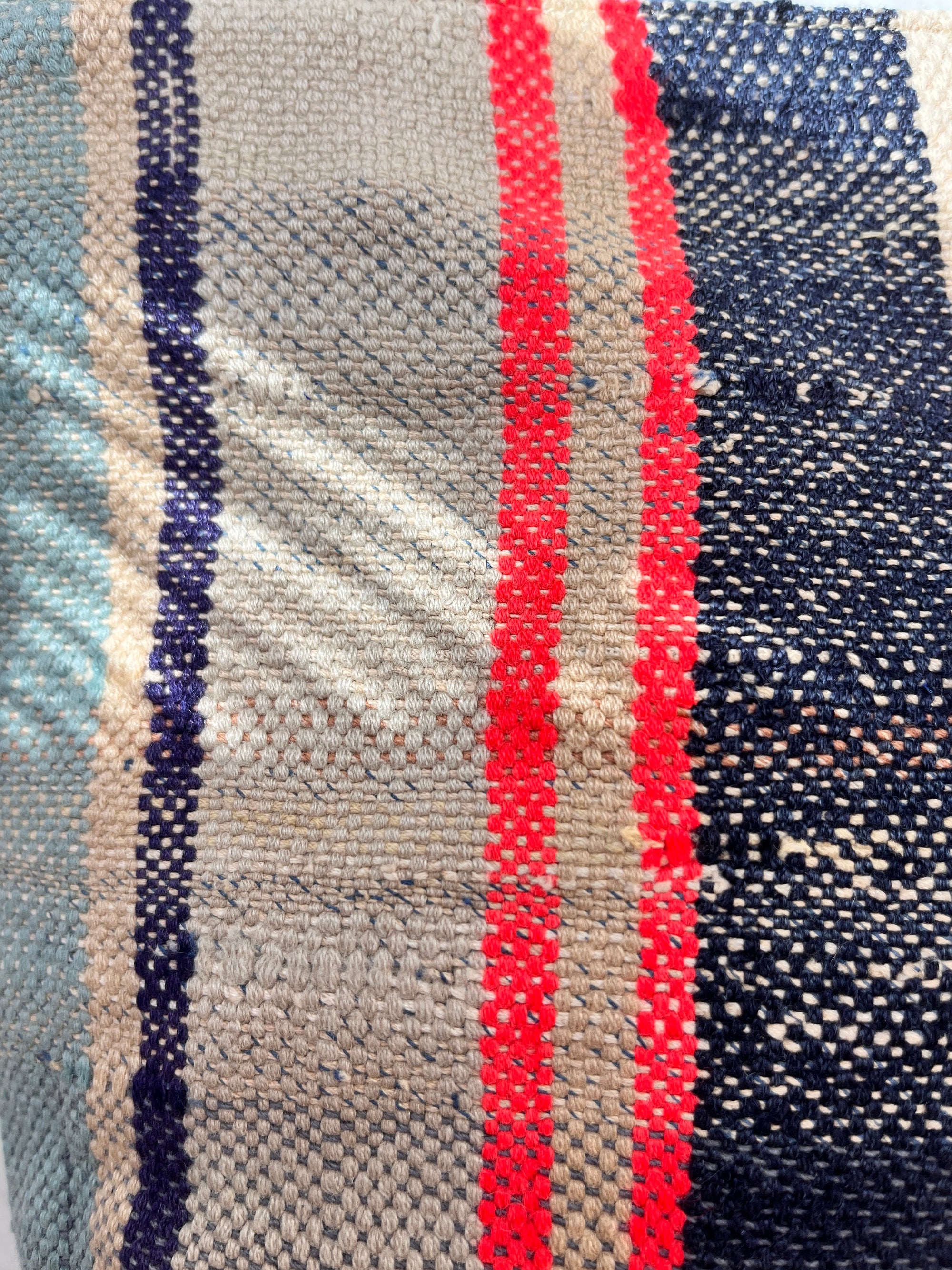 Eine Nahaufnahme des TASCHE-Stoffes von LEY! zeigt leuchtende vertikale Streifen in Marine, Rot, Beige und Hellblau. Die strukturierte Bindung und die Fadendetails machen ihn perfekt für einzigartige Einzelstück-Designs oder handgenähte Taschen.