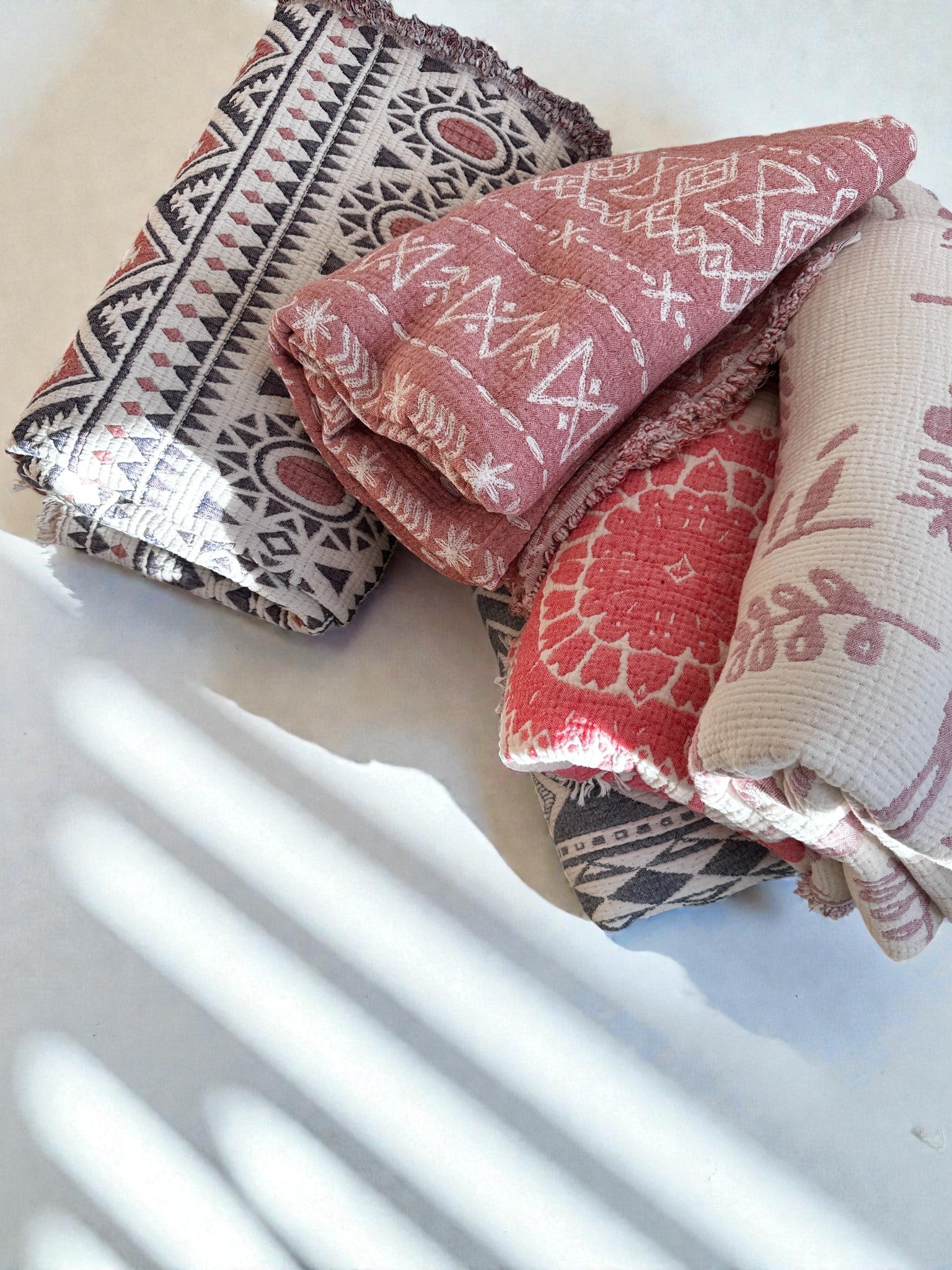 Die CALMA Musselin Decke von LEY! in Rosé-Weiß (2,30 x 2,40 m) zeigt weiche geometrische und florale Muster - ein atmungsaktives Textil, das sich perfekt für Boho-inspirierte Akzente oder kuschelige Schichten zu Hause eignet.