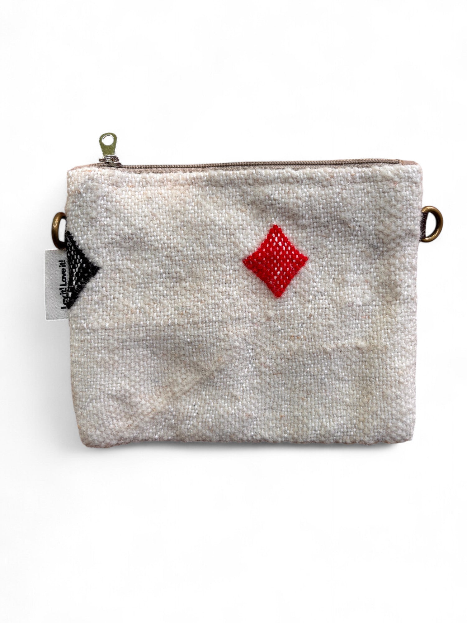 Die LEY! Tasche - Colorful Line - 15x20cm ist eine kleine beigefarbene Schurwolle-Tasche mit strukturierter Oberfläche, Reißverschluss, rotem Rauten- und schwarzem Spaten-Muster, Metallringen auf jeder Seite, weißem linken Anhänger und Teil der Colorful Line Kollektion.