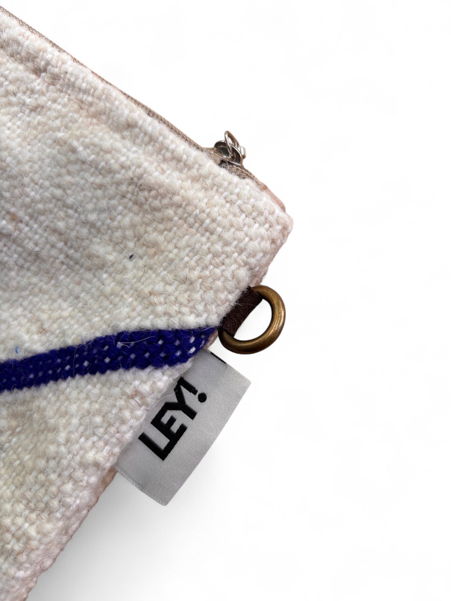 Nahaufnahme der LEY! Tasche - Classic Line - 15x20cm: eine Stofftasche mit Reißverschluss, Metallring, blauem Streifendetail und weißem "LEY!"-Tag-Schurwolle-Design, inspiriert von Handarbeit Marrakesch auf weißem Hintergrund.
