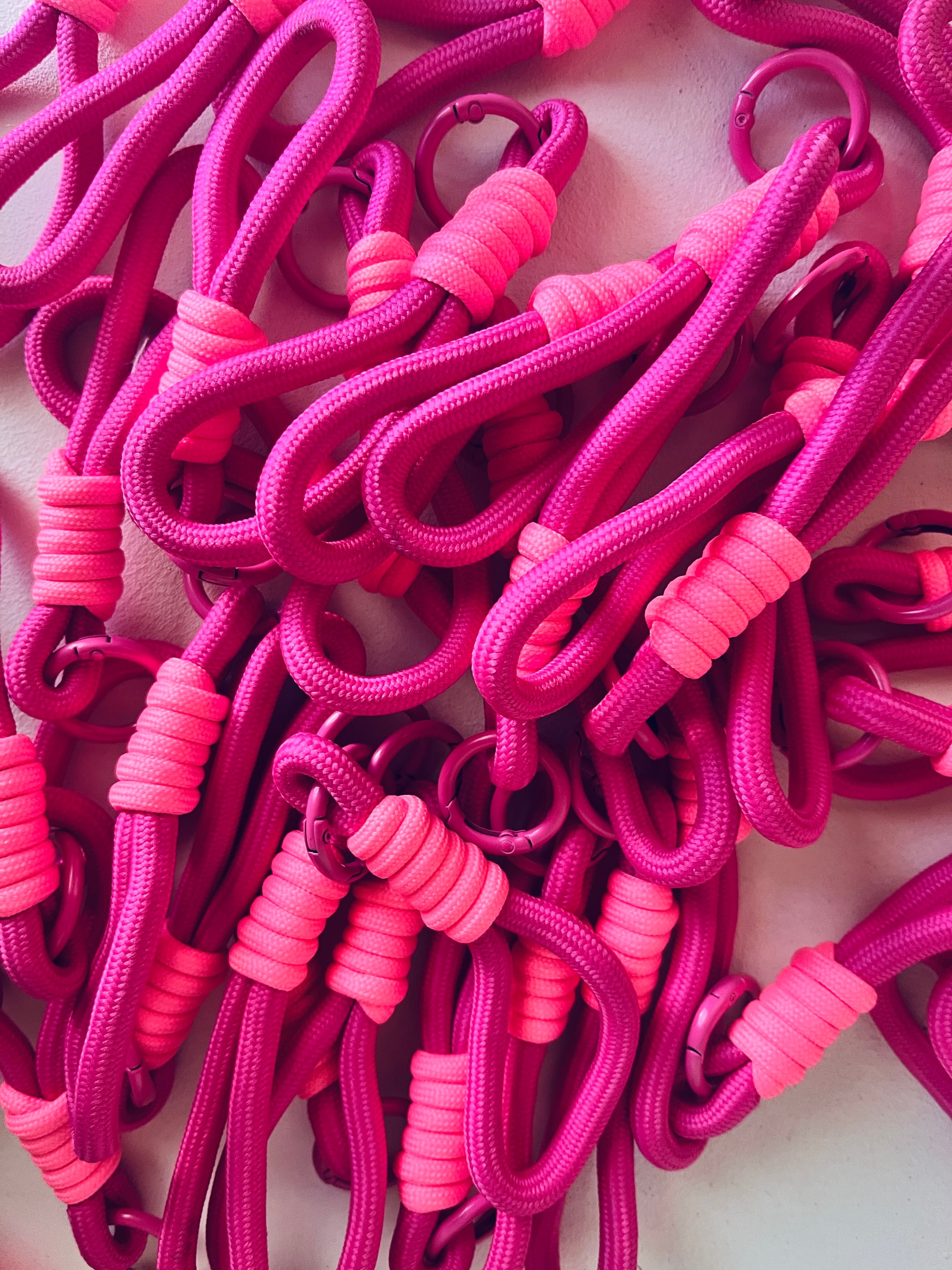 Eine Nahaufnahme von LEY! Schlüsselanhänger - pink zeigt ineinander verschlungene magentafarbene und pinkfarbene Spiralkordeln mit Kunststoffhaken - ideal als stylisches Accessoire für Schlüssel oder Taschen.