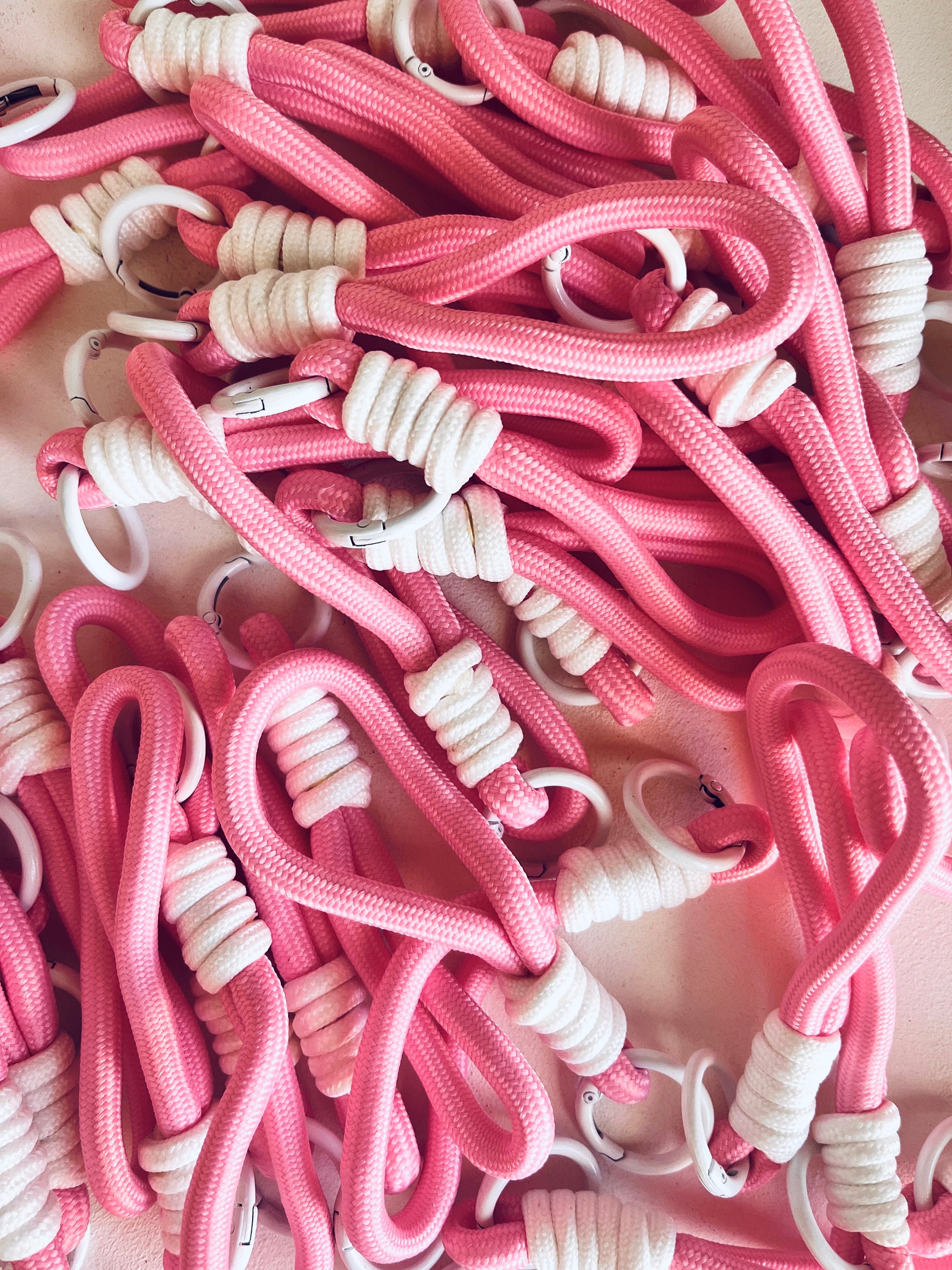 Ein verworrener Haufen LEY! Schlüsselanhänger - rosa, mit rosafarbenen Kordeln mit weißen Windungen und Kunststoffringen - ideal als Schlüsselanhänger oder trendiges Taschenaccessoire.