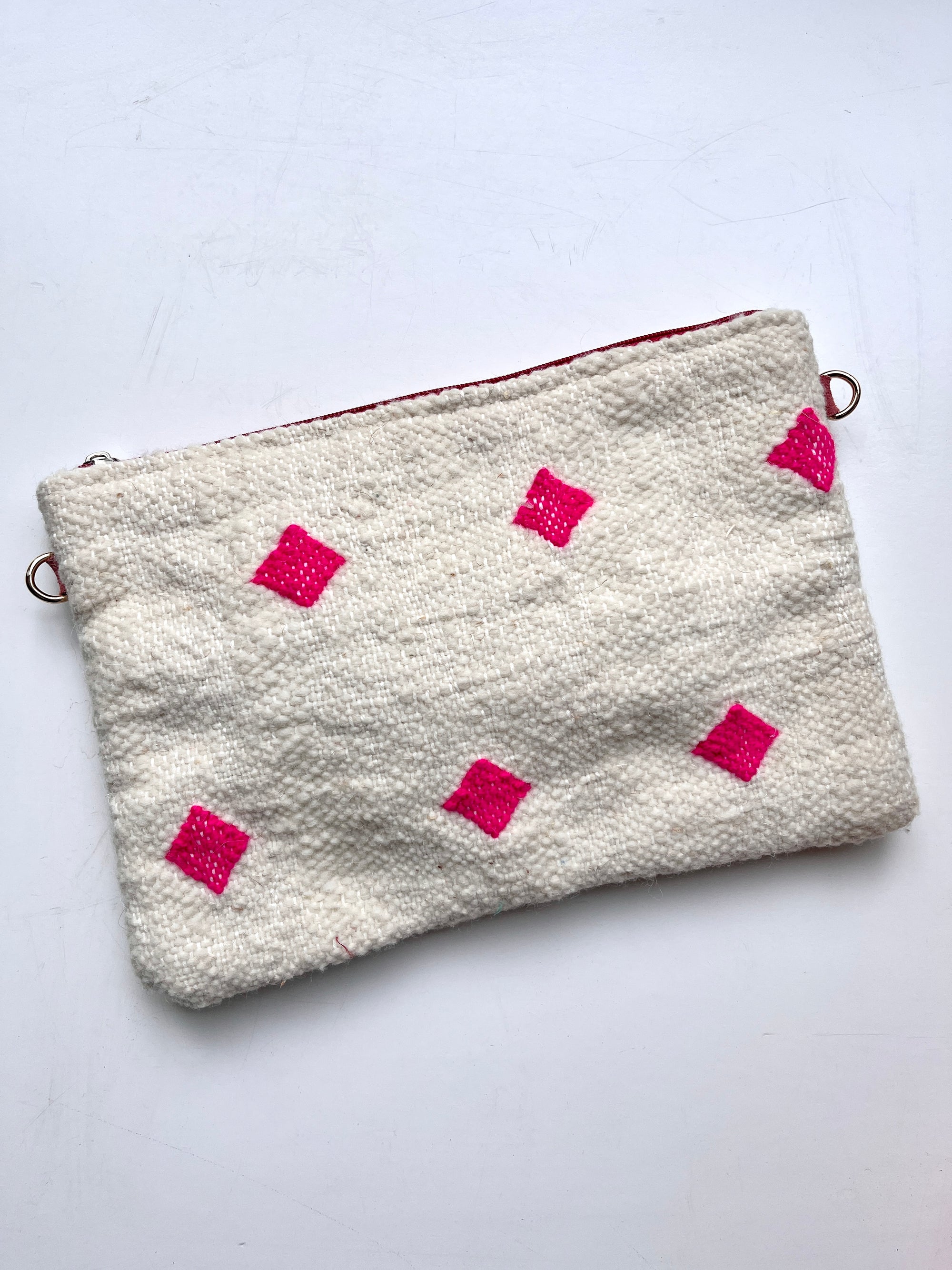 Die LEY! Tasche - Mona Pink (20x30cm) ist eine weiße, strukturierte Reißverschlusstasche mit auffälligen, rosafarbenen Rauten, inspiriert von der Handarbeit Marrakeschs mit einem Hauch von Colorful Line, auf einem schlichten weißen Hintergrund.
