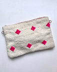 Die LEY! Tasche - Mona Pink (20x30cm) ist eine weiße, strukturierte Reißverschlusstasche mit auffälligen, rosafarbenen Rauten, inspiriert von der Handarbeit Marrakeschs mit einem Hauch von Colorful Line, auf einem schlichten weißen Hintergrund.