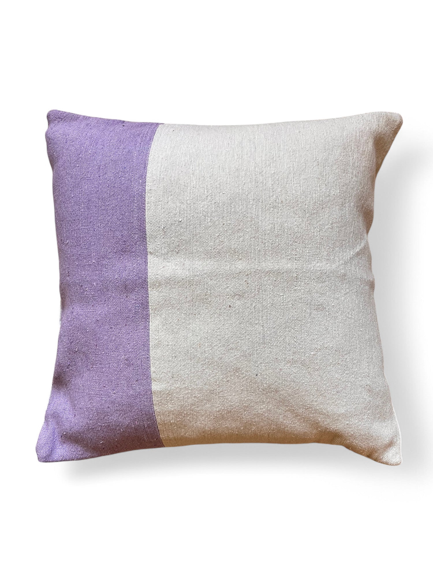 Das Kissen - Dilara 60x60 von LEY! zeichnet sich durch ein schlichtes, quadratisches Design mit einer lavendelfarbenen linken Seite und einer gebrochen weißen rechten Seite aus, die auf einem schlichten weißen Hintergrund stehen.