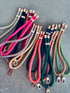 Eine Vielzahl von bunten LEY! Schlüsselanhänger-Kordeln - grün, pink, schwarz, beige, orange und gold - mit metallischen Verschlüssen und Kappen sind in überlappenden Reihen angeordnet. Diese trendigen Farben halten dein Handy immer griffbereit.