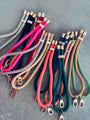 Eine Vielzahl von bunten LEY! Schlüsselanhänger-Kordeln - grün, pink, schwarz, beige, orange und gold - mit metallischen Verschlüssen und Kappen sind in überlappenden Reihen angeordnet. Diese trendigen Farben halten dein Handy immer griffbereit.