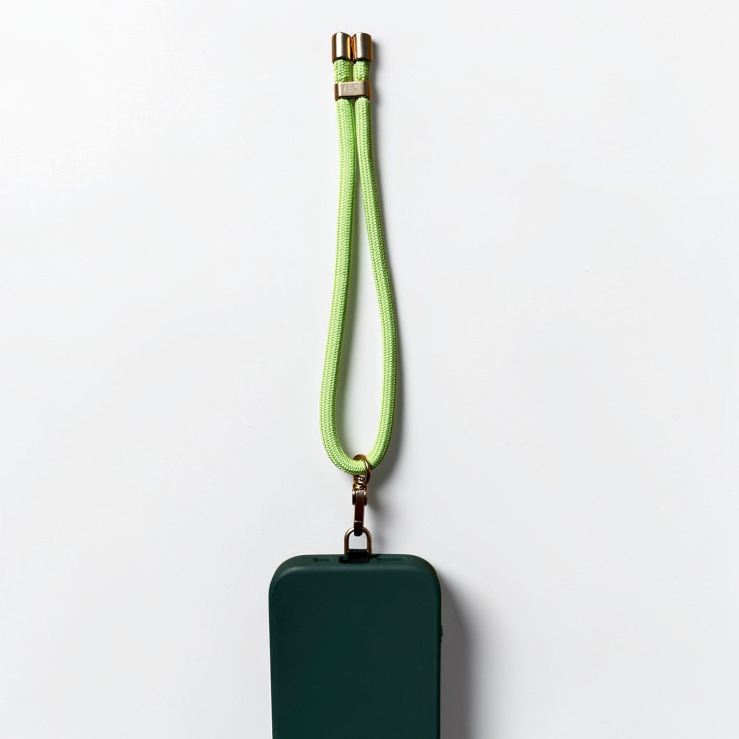 Ein pastellgrünes, rechteckiges Schlüsselanhänger-Etui von LEY! mit passendem Armband und goldenen Beschlägen vor einem schlichten weißen Hintergrund.