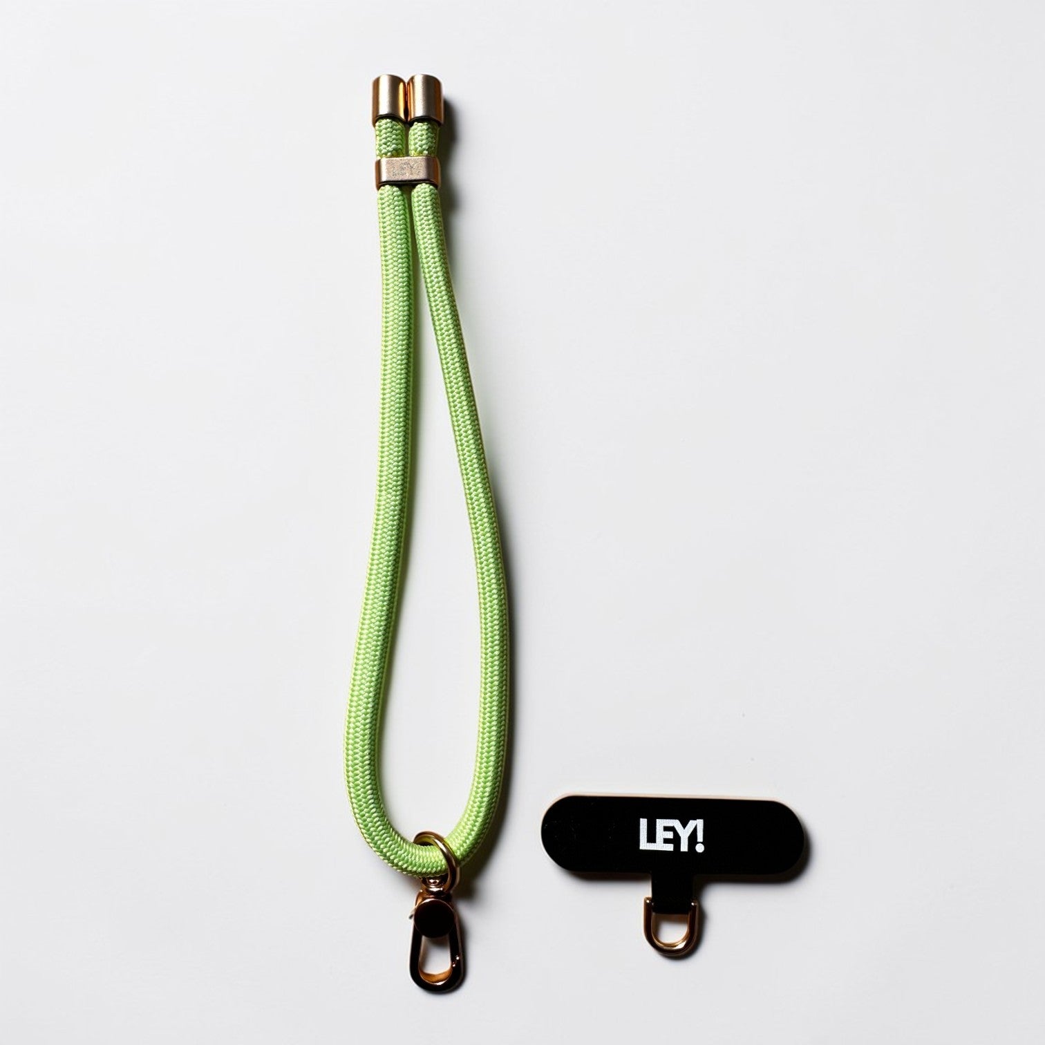 Ein pastellgrüner Schlüsselanhänger von LEY! mit Metallclips und abnehmbarem schwarzem Badgehalter mit weißem Schriftzug "LEY!" auf weißem Hintergrund.