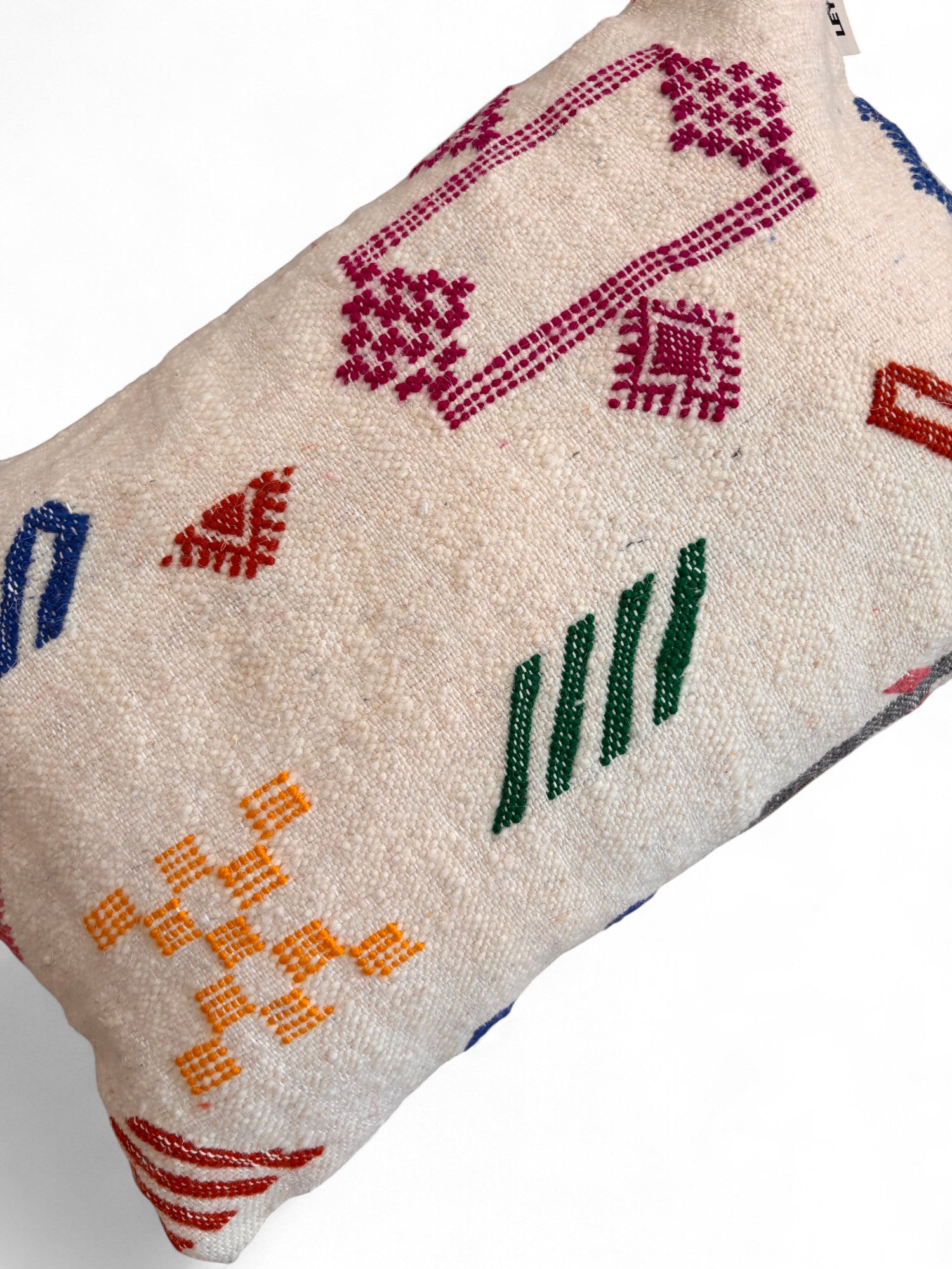 Das LEY! Kissen - Colorful Line - 40 x 60 von LEY! ist ein rechteckiges, cremefarbenes Kissen mit farbenfroher, geometrischer Stickerei in Rot, Lila, Grün, Blau und Gelb auf einfarbigem Hintergrund.
