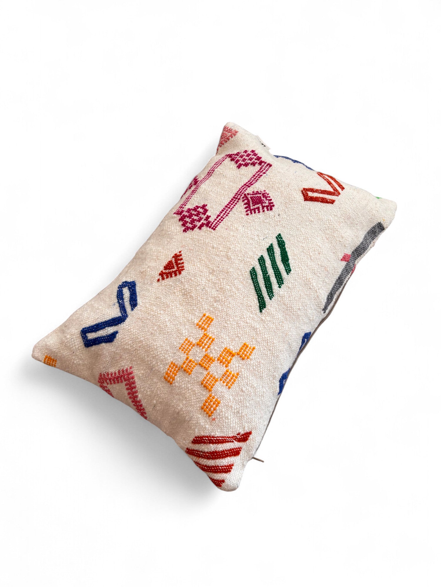 Das LEY! Kissen - Colorful Line - 40 x 60 von LEY! ist ein rechteckiges, beigefarbenes Kissen mit leuchtend roter, gelber, grüner, blauer und pinker geometrischer Stickerei auf weißem Grund - hergestellt in Handarbeit in Marrakesch.