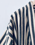 Nahaufnahme des KIMONO - MEDITERANE - SCHWARZ - WEIß von THE DANISH GIRL INTERIOR, mit strukturierten schwarzen und weißen Streifen in vertikalen und diagonalen Mustern auf hellblauem Hintergrund mit Richtungswechsel an den Nähten.
