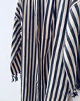 Mehrere KIMONO - MEDITERANE - SCHWARZ - WEIß Roben von THE DANISH GIRL INTERIOR mit schwarz-weißen Streifen und kleinen Quasten hängen aneinander und bilden ein auffälliges, sich wiederholendes Muster vor einem schlichten weißen Hintergrund.