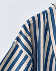 Eine Nahaufnahme des KIMONO - MEDITERANE - BLAU - WEIß von THE DANISH GIRL INTERIOR mit blauen und weißen vertikalen und diagonalen Streifen auf strukturiertem Stoff vor einem schlichten weißen Hintergrund.