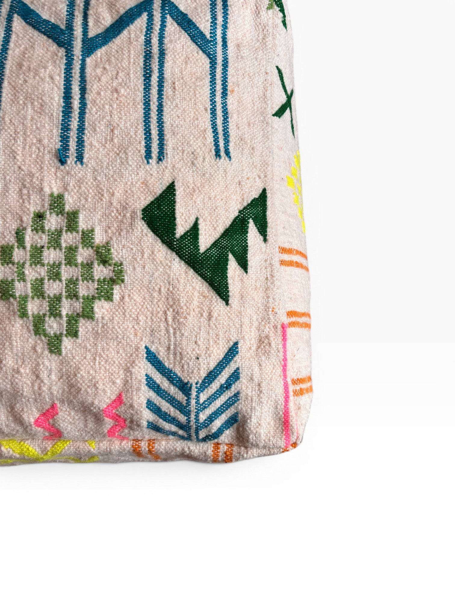 Eine Nahaufnahme einer Tasche aus gewebtem Stoff mit geometrischen Mustern in Grün, Blau, Rosa und Gelb auf hellem Grund - ähnlich wie beim LEY! Bodenkissen - Colorful Line - Mara. Nur der untere Teil und die Ecke der Tasche sind zu sehen.