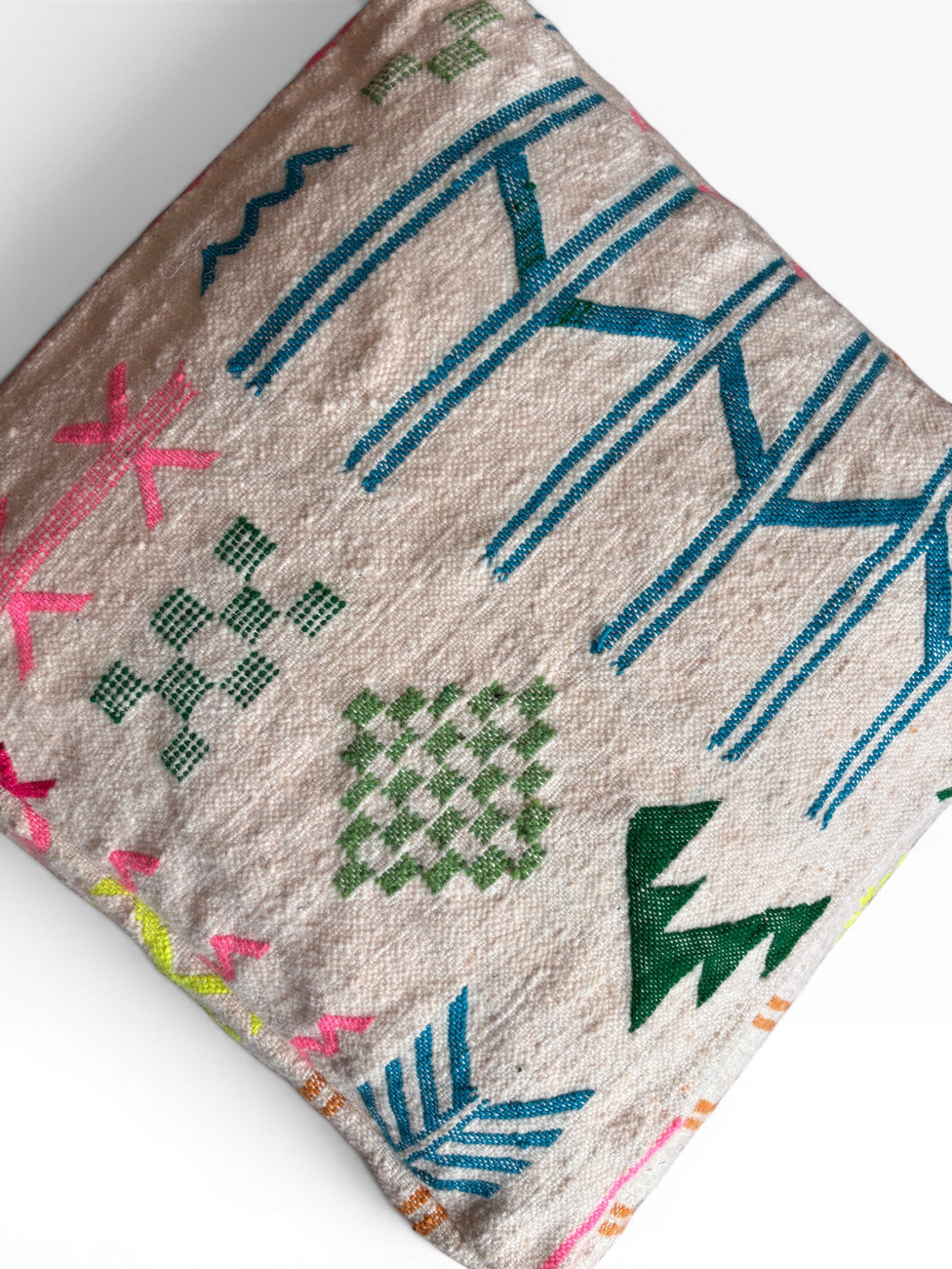Das LEY! Bodenkissen - Colorful Line - Mara zeichnet sich durch einen cremefarbenen Untergrund mit farbenfrohen geometrischen und abstrakten Stickereien in blauer, grüner, rosa und gelber Wolle aus. Das dekorative Kissen ist vor einem weißen Hintergrund abgebildet.