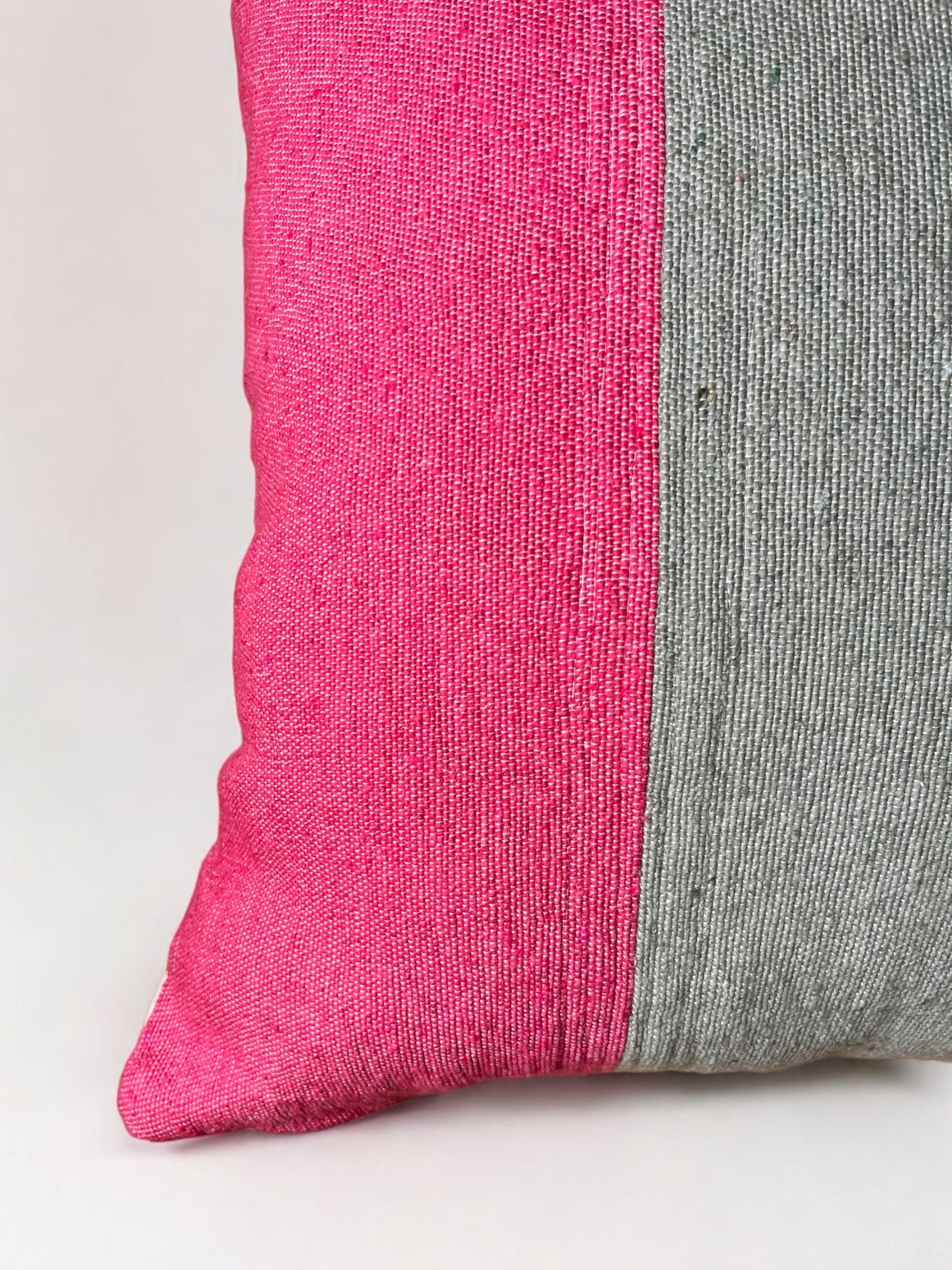 Eine Nahaufnahme des LEY! Kissen - Merva 60x60: zwei strukturierte Stoffe - helles Rosa auf der linken Seite, helles Grau auf der rechten Seite - werden durch eine vertikale Naht geteilt, wodurch ein stilvoller und einzigartiger Baumwollkissenbezug entsteht.