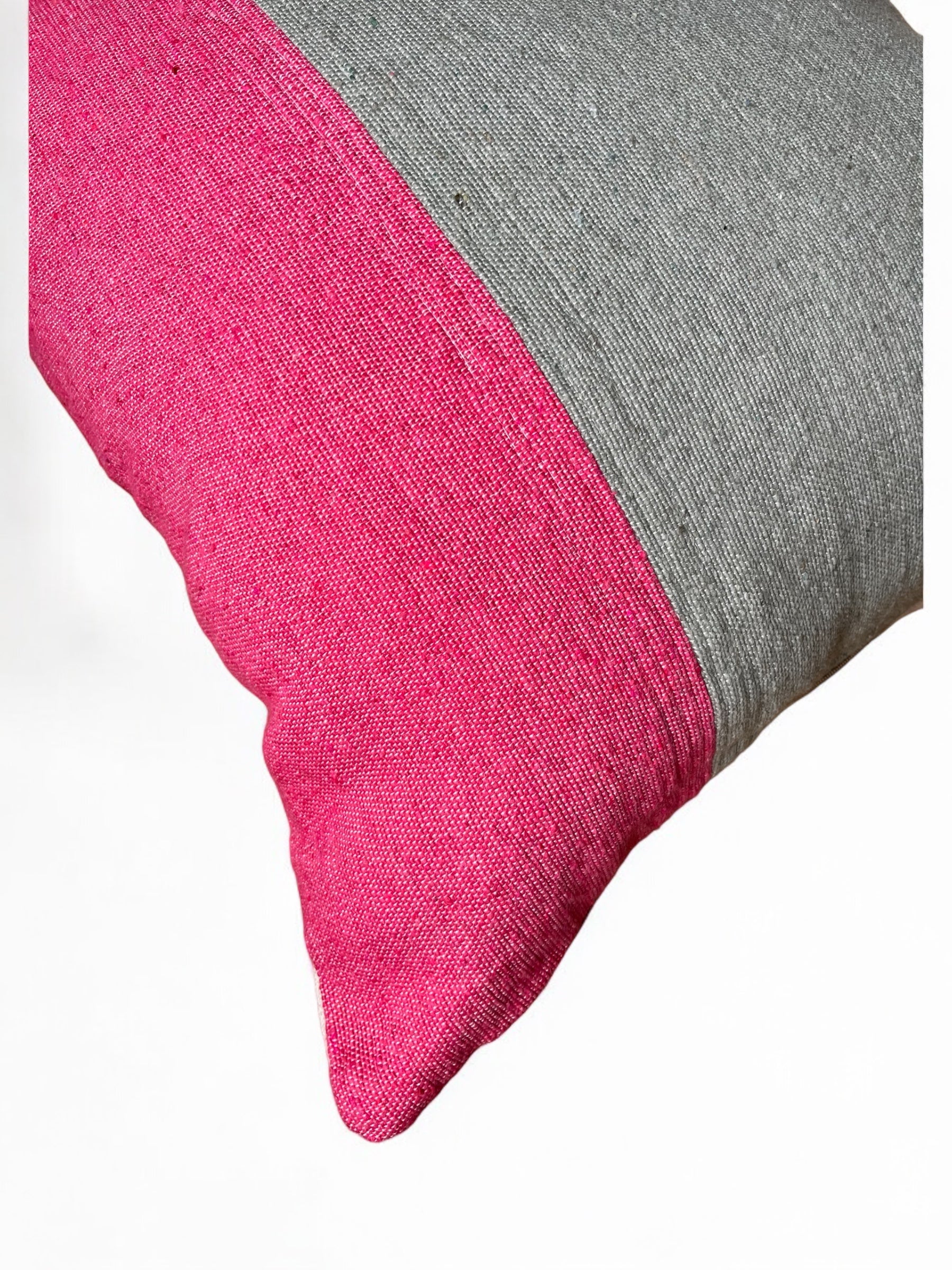 Eine Nahaufnahme des LEY! Kissen - Merva 60x60: ein handgefertigter quadratischer Baumwoll-Kissenbezug mit leuchtend rosa und hellgrauen diagonalen Blöcken, dargestellt vor einem weißen Hintergrund.