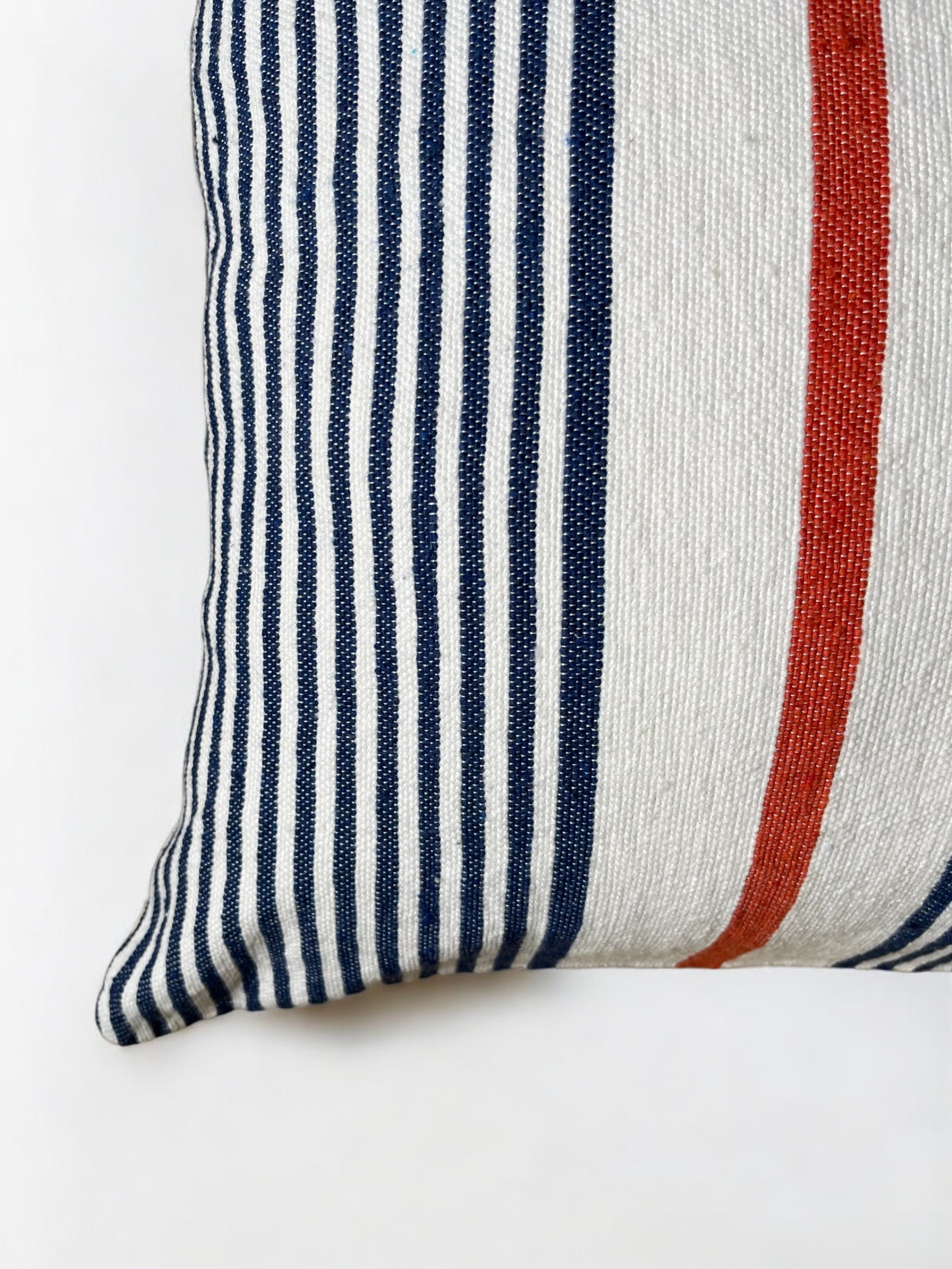 Eine Nahaufnahme des LEY! Kissen - Parosa 60x60 zeigt seinen handgefertigten gewebten Bezug mit vertikalen blauen und weißen Streifen, einem kräftigen roten Streifen auf Weiß - ideal als Outdoor-Kissen.