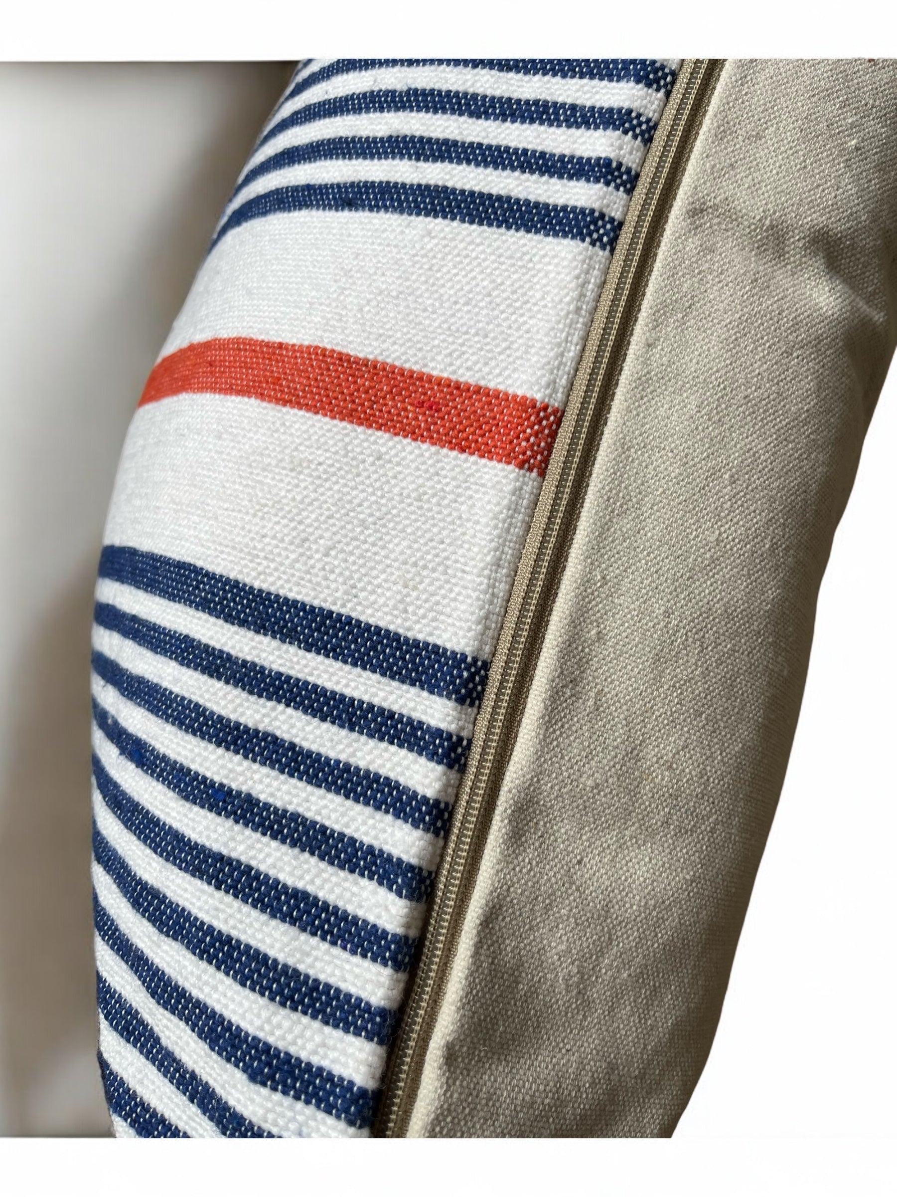 Nahaufnahme des LEY! Kissen - Parosa 60x60, mit blauen und weißen Streifen, einem kräftigen roten Akzent und einem beigen Reißverschluss am Rand - ideal als Outdoor-Kissen - vor einem weißen Hintergrund.