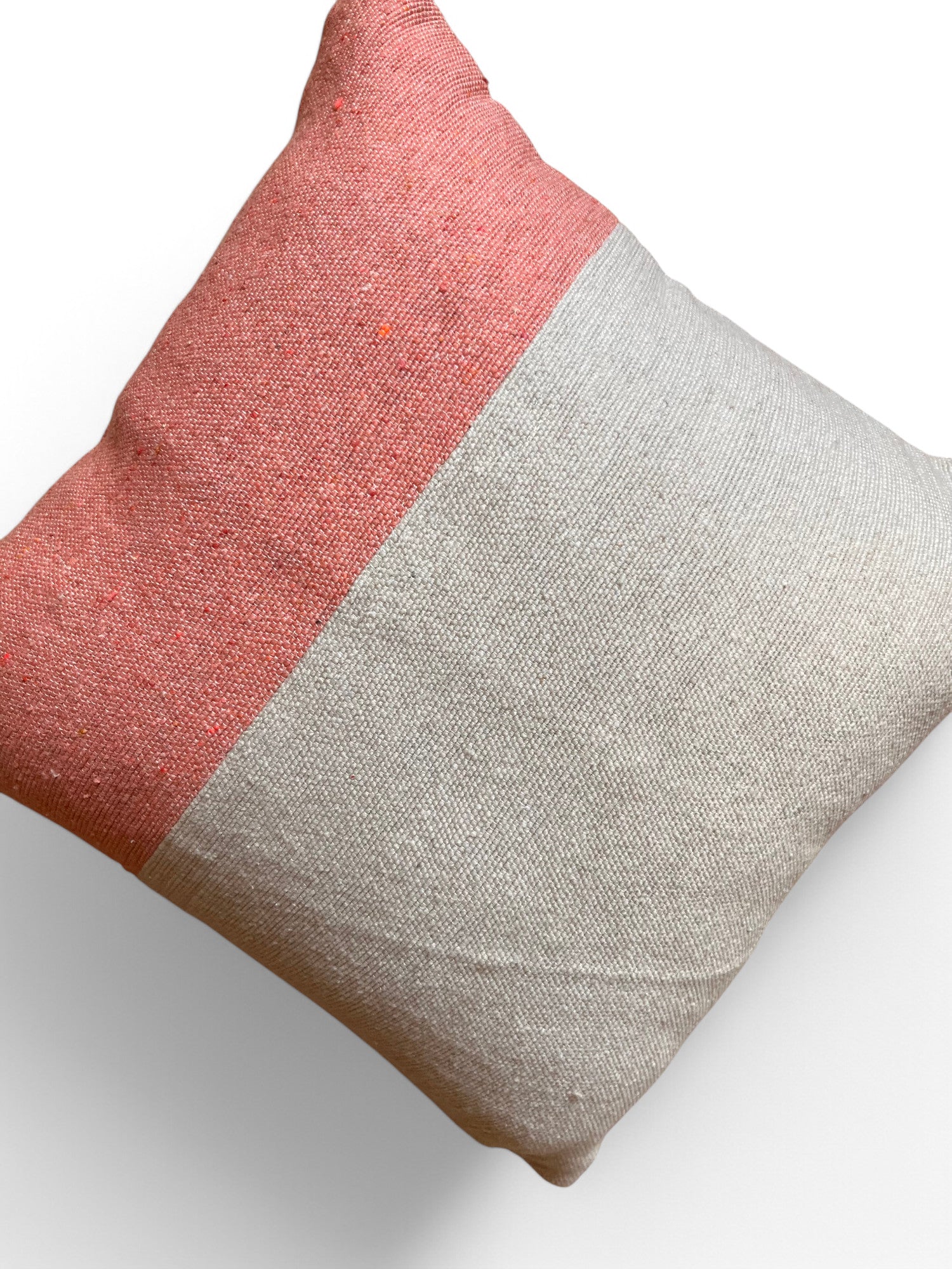 Das LEY! Kissen - Amela 40x40 ist ein quadratisches Kissen mit handgefertigtem Marrakesch-Strukturstoff, dessen obere Hälfte korallenrosa und dessen untere Hälfte hellbeige ist und das sich elegant auf einem weißen Hintergrund präsentiert.