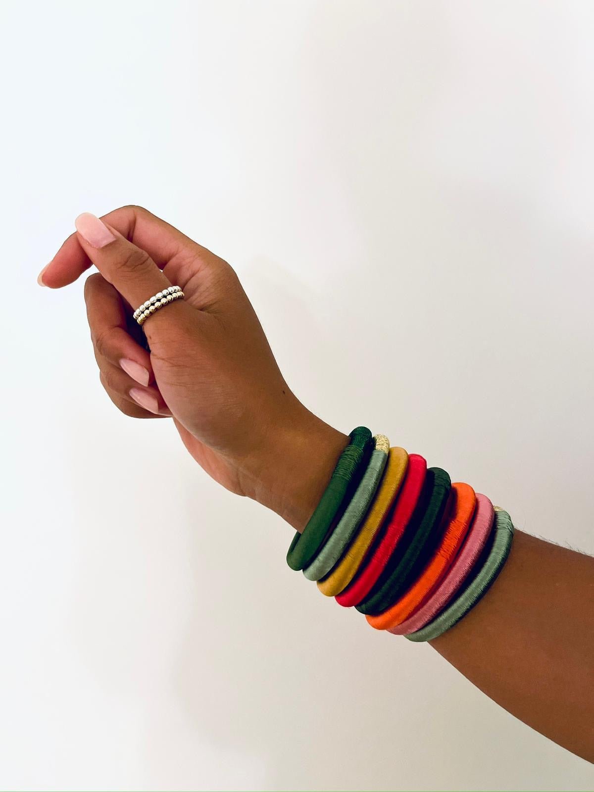 Eine Hand trägt den bordeauxfarbenen Armreif von LEY! sowie bunte Bangles vor weißem Hintergrund - ein einzigartiges, marokkanisch inspiriertes Geschenk.