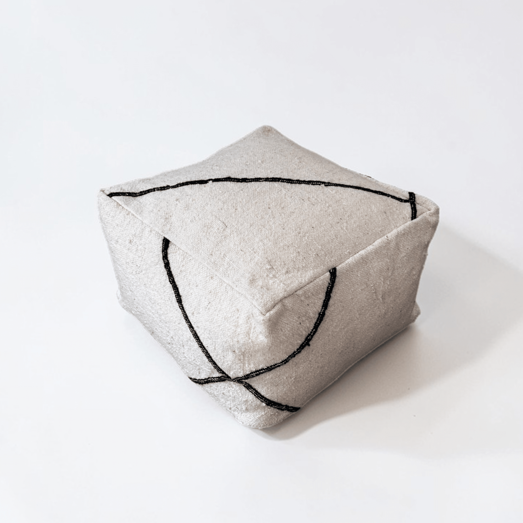 Das LEY! Kleines Bodenkissen - Meli Mini ist ein quadratischer, hellgrauer Schurwolle-Pouf mit minimalistischen schwarzen, geschwungenen Linien, der in Handarbeit hergestellt wird - ein moderner Akzent für jeden Raum.