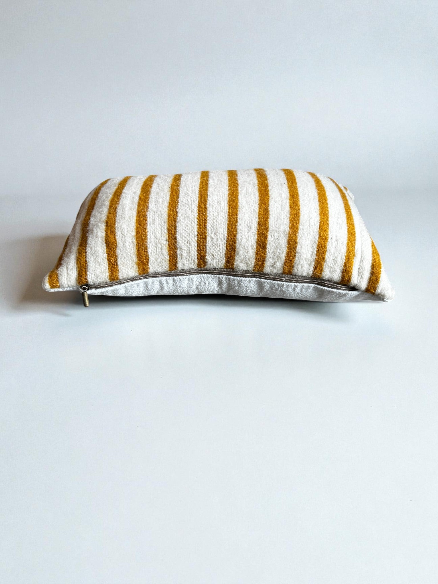 Das LEY! Kissen - WINTER EDITION - SONNE - 30 x 50 hat gelbe und weiße Streifen auf der Oberseite, einen sichtbaren Reißverschluss auf der hellen Unterseite und liegt auf einer unifarbenen weißen Oberfläche - ideal für die Winter Edition Kissen Kollektion.