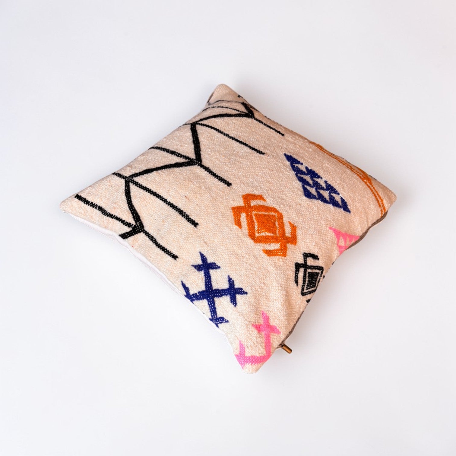 Das LEY! Kissen - Colorful Line - 50 x 50 von LEY! ist ein quadratisches, beigefarbenes Schurwolle-Kissen mit abstrakten, geometrischen Mustern in Schwarz, Orange, Blau und Rosa auf einem einfarbig weißen Hintergrund.
