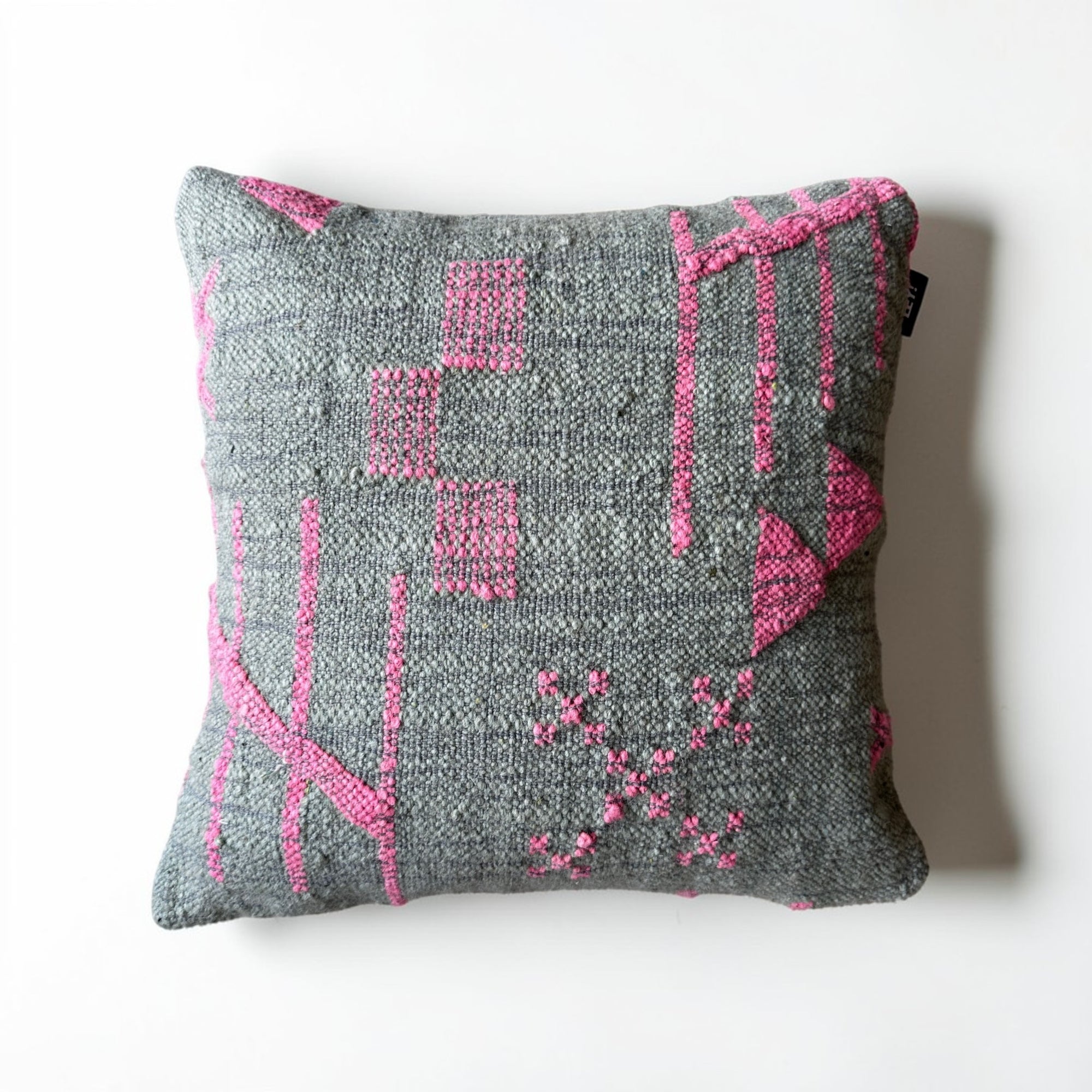 Das LEY! Kissen - Colorful Line - SAGE EDITION (50x50 cm) von LEY! ist ein handgefertigtes quadratisches Kissen mit strukturiertem grauem Stoff und abstrakten rosa geometrischen Mustern auf weißem Hintergrund.