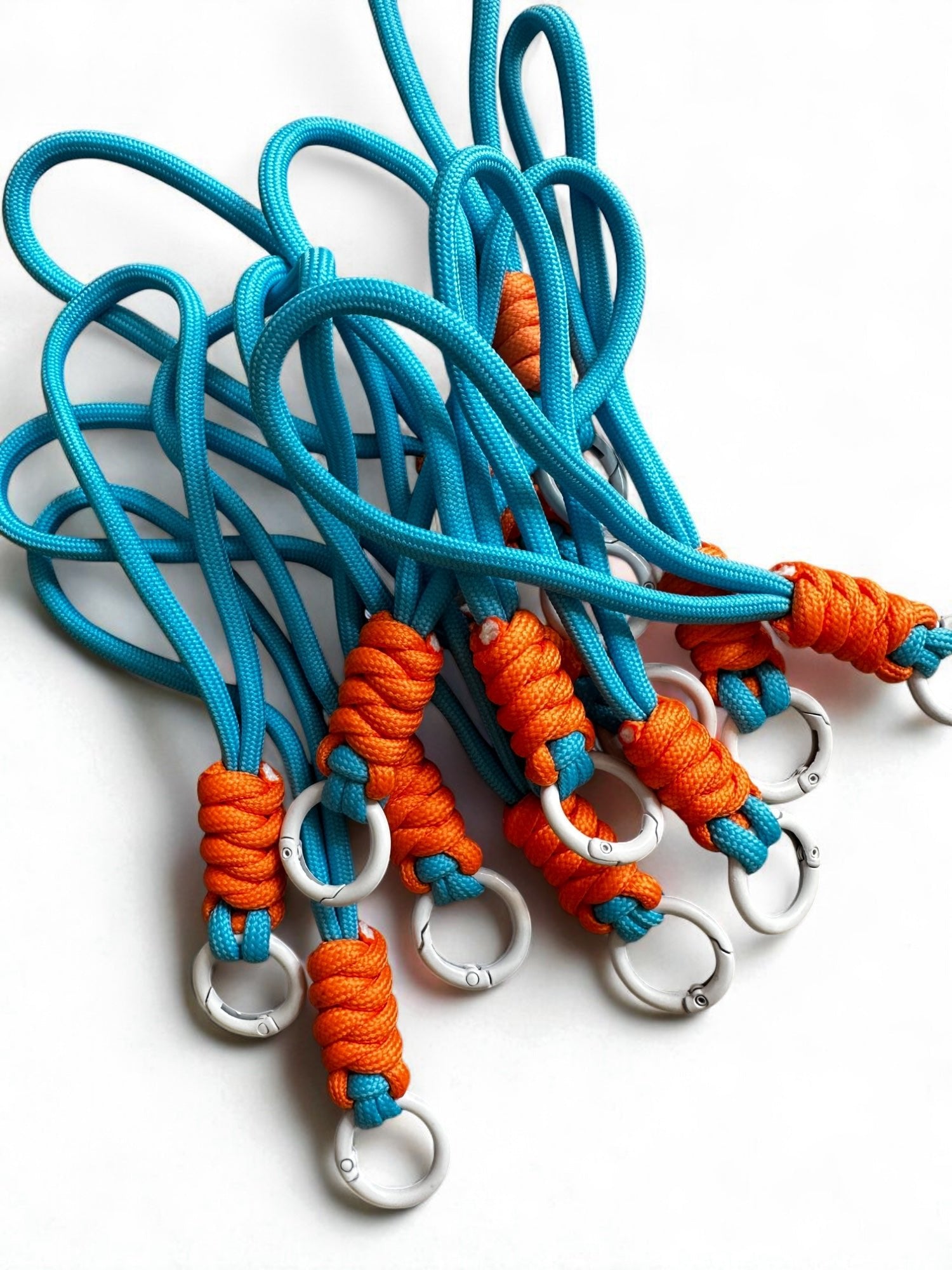 Ein Set von LEY! Schlüsselanhänger - orange-blau mit blauem Paracord und orange geflochtenen Griffen, ideal für Taschen, auf weißem Hintergrund.