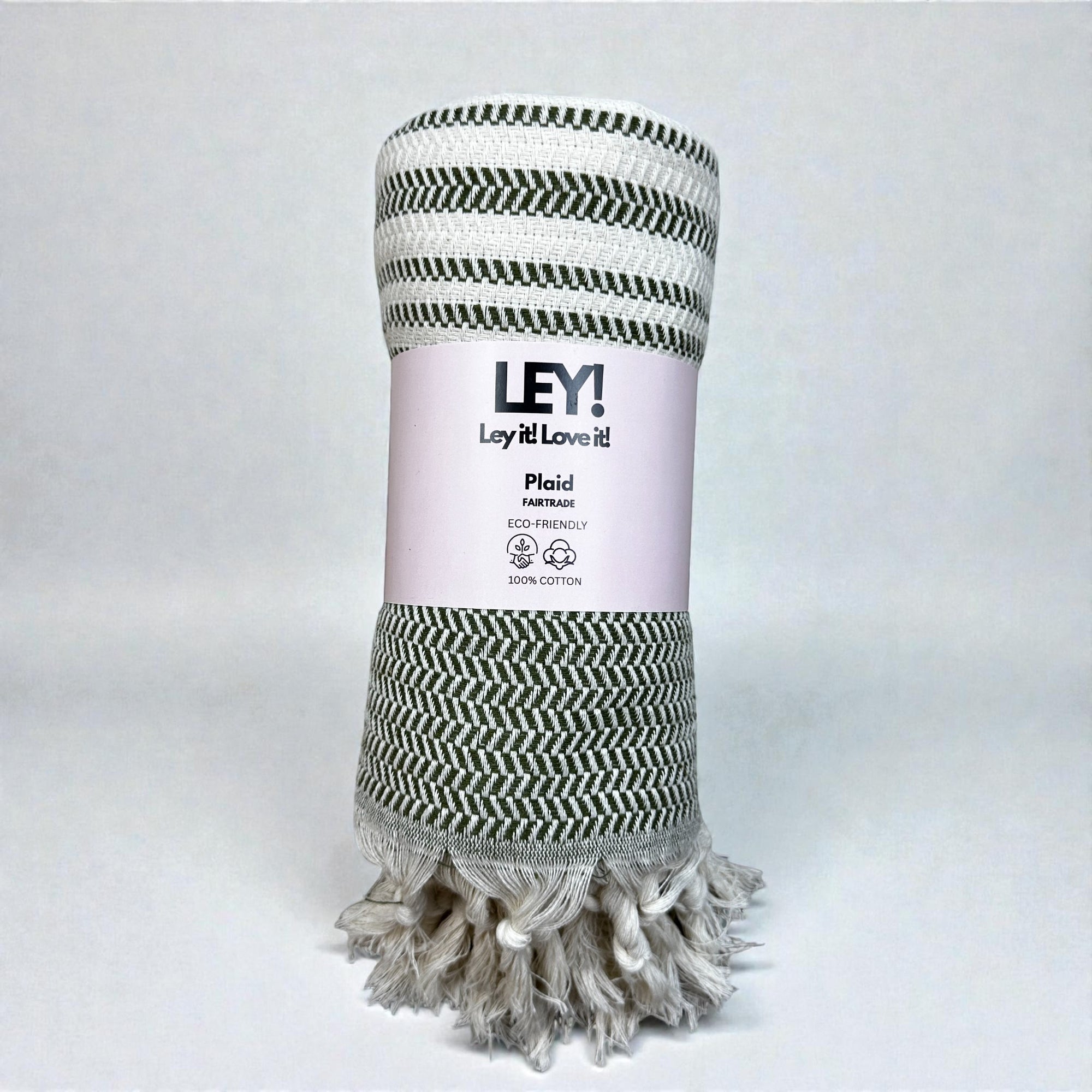 Eine aufgerollte grün-weiße "LEY! Plaid - Zickzack - Olive" mit ausgefransten Rändern, beschriftet mit "LEY! Lay it! Love it!" 100% Baumwolle und umweltfreundlich. Perfekt als Picknickdecke oder kuscheliges Saunatuch. Schlichter weißer Hintergrund.