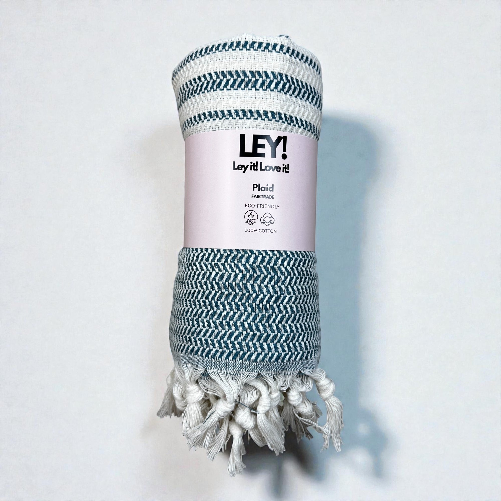 Eine gerollte, blau-weiß gefranste Baumwolldecke mit der Aufschrift "LEY! Plaid - Zickzack - Petrol" von LEY! - die perfekte umweltfreundliche Picknickdecke oder Saunatuch, abgebildet auf einem schlichten weißen Hintergrund.