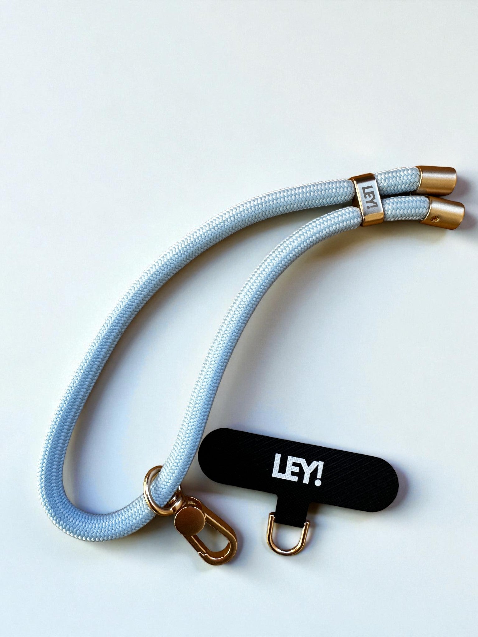 Ein hellblauer Schlüsselanhänger von LEY! mit goldenen Metallclips und einem schwarzen "LEY!"-Anhänger, ideal um Schlüssel griffbereit zu halten, abgebildet auf weißem Hintergrund.